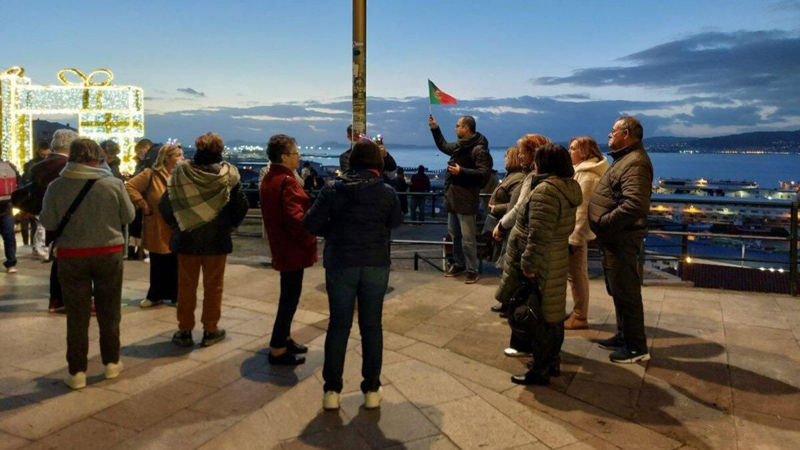 Un grupo de turistas portugueses, ayer en el Paseo de Alfonso, junto a un guía con la bandera.