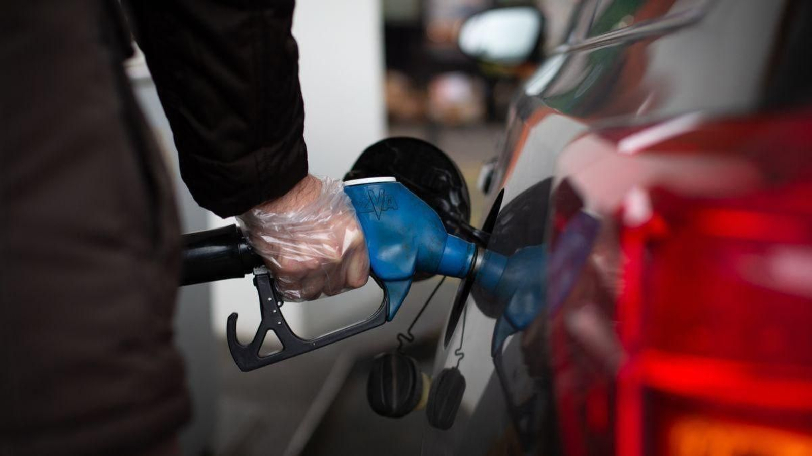 Un hombre llena el tanque de combustible de su vehículo en una gasolinera.
