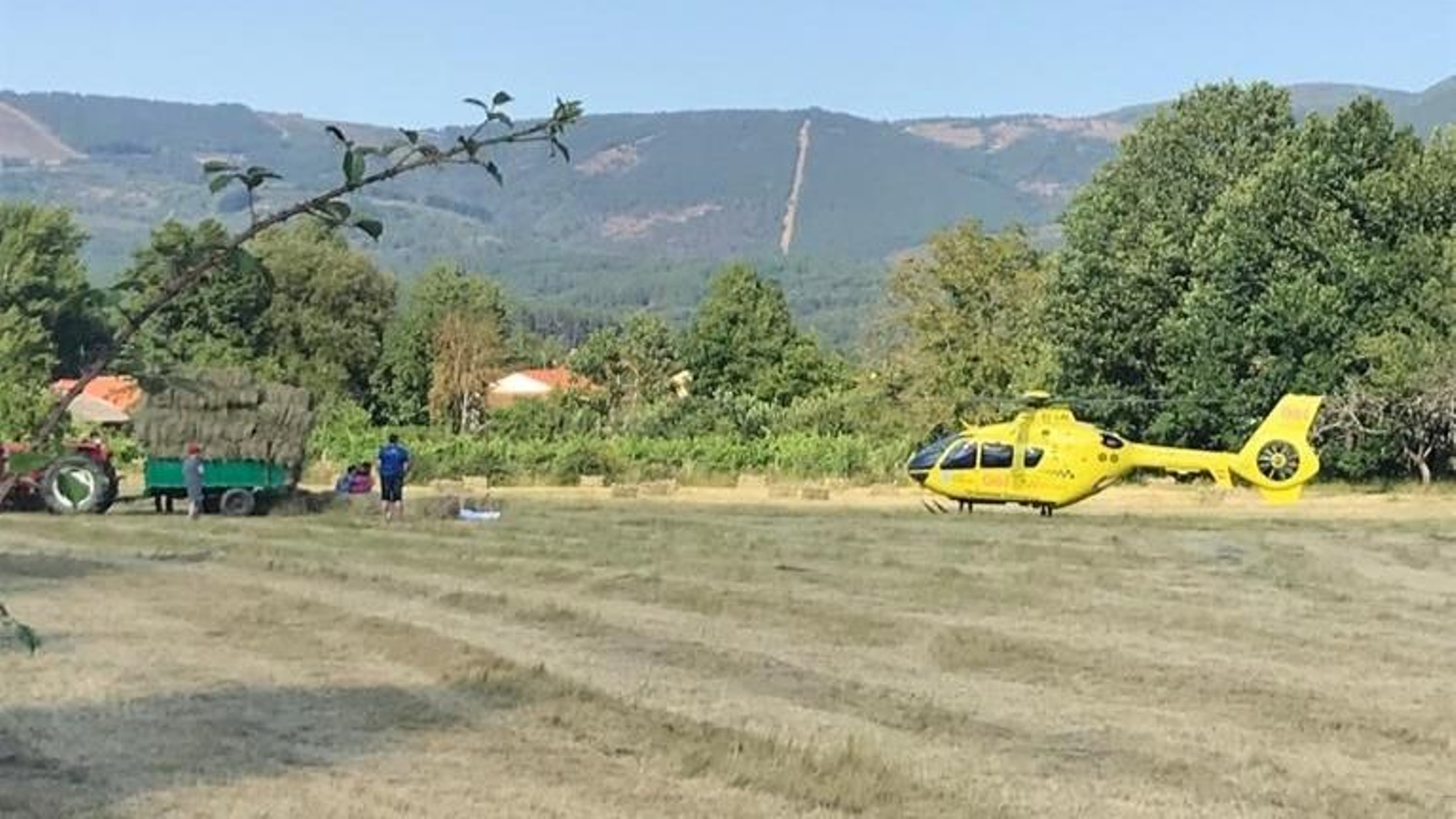 El helicóptero del 061, junto al tractor cargado de pacas, del que se cayó el fallecido.