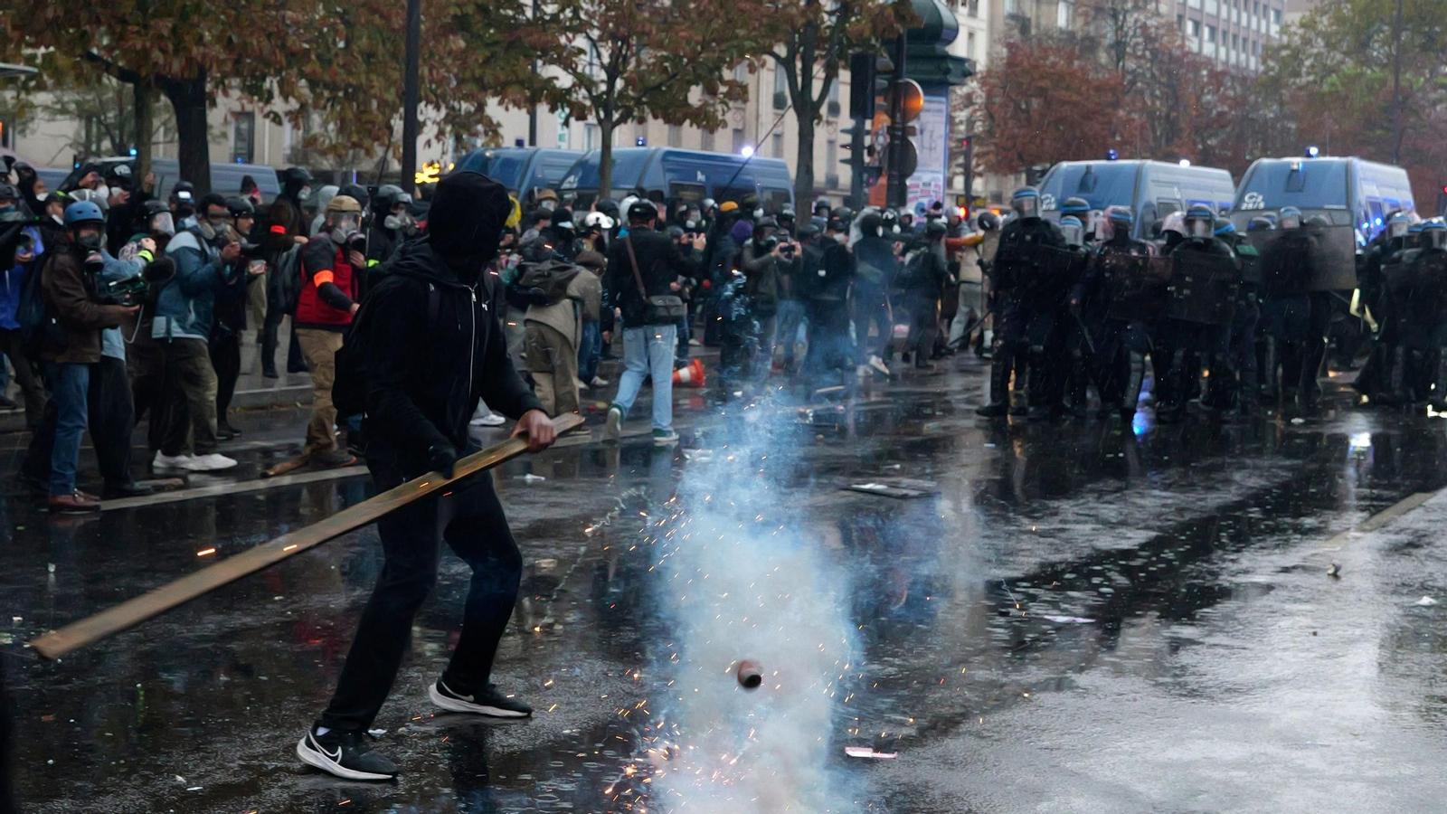Un manifestante sostiene una tablilla de madera frente a un cordón policial durante una protesta que exige poder adquisitivo, la preservación de los servicios públicos y justicia fiscal y social.