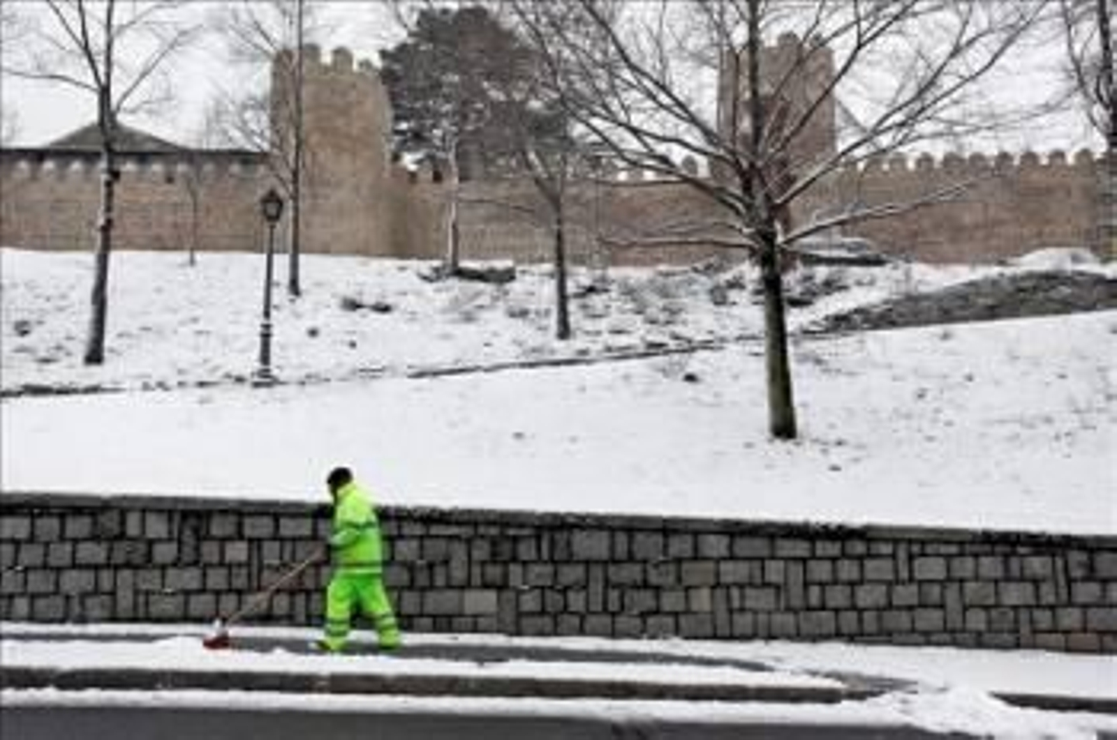 Un operario retira la nieve caída junto a la muralla de Ávila. (Foto: Raúl Sanchidrián)