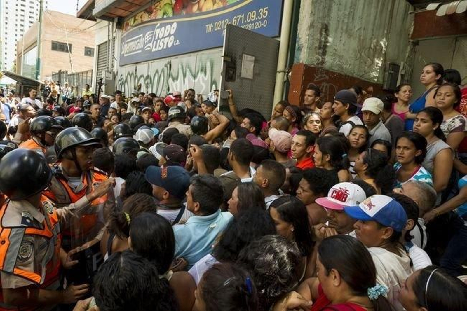 Una multitud se agolpa a las puertas de un supermercado durante una protesta por falta de suministros.