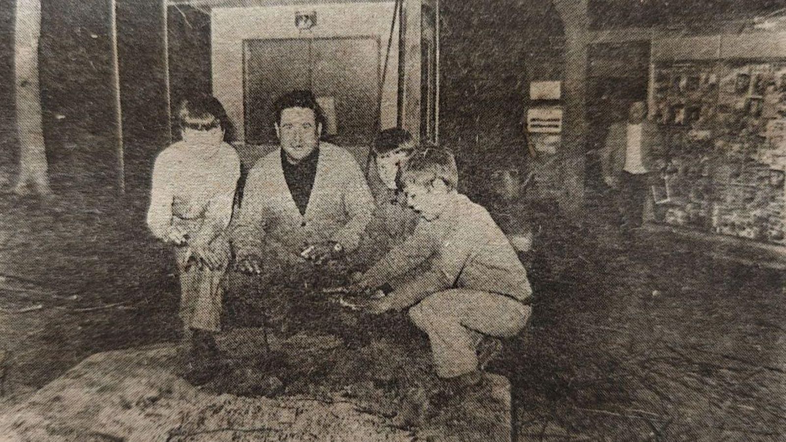 Un hombre y tres niños, calentando las manos en los restos de la más que imprudente hoguera.