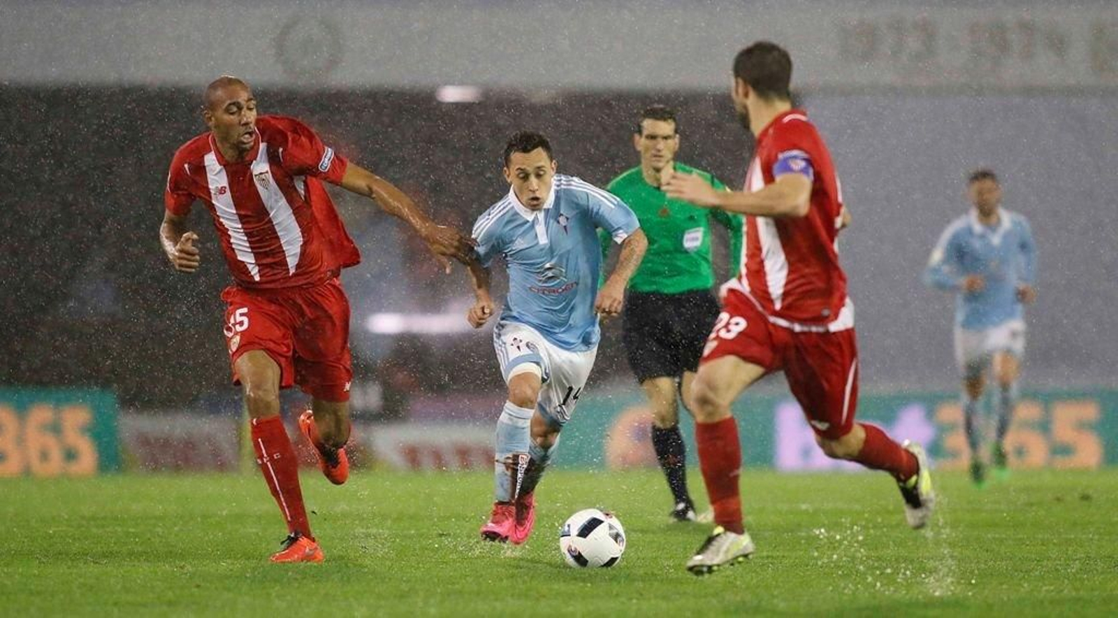 Fabián Orellana conduce el balón entre N'Zonzi y Coke sobre el encharcado césped de Balaídos.