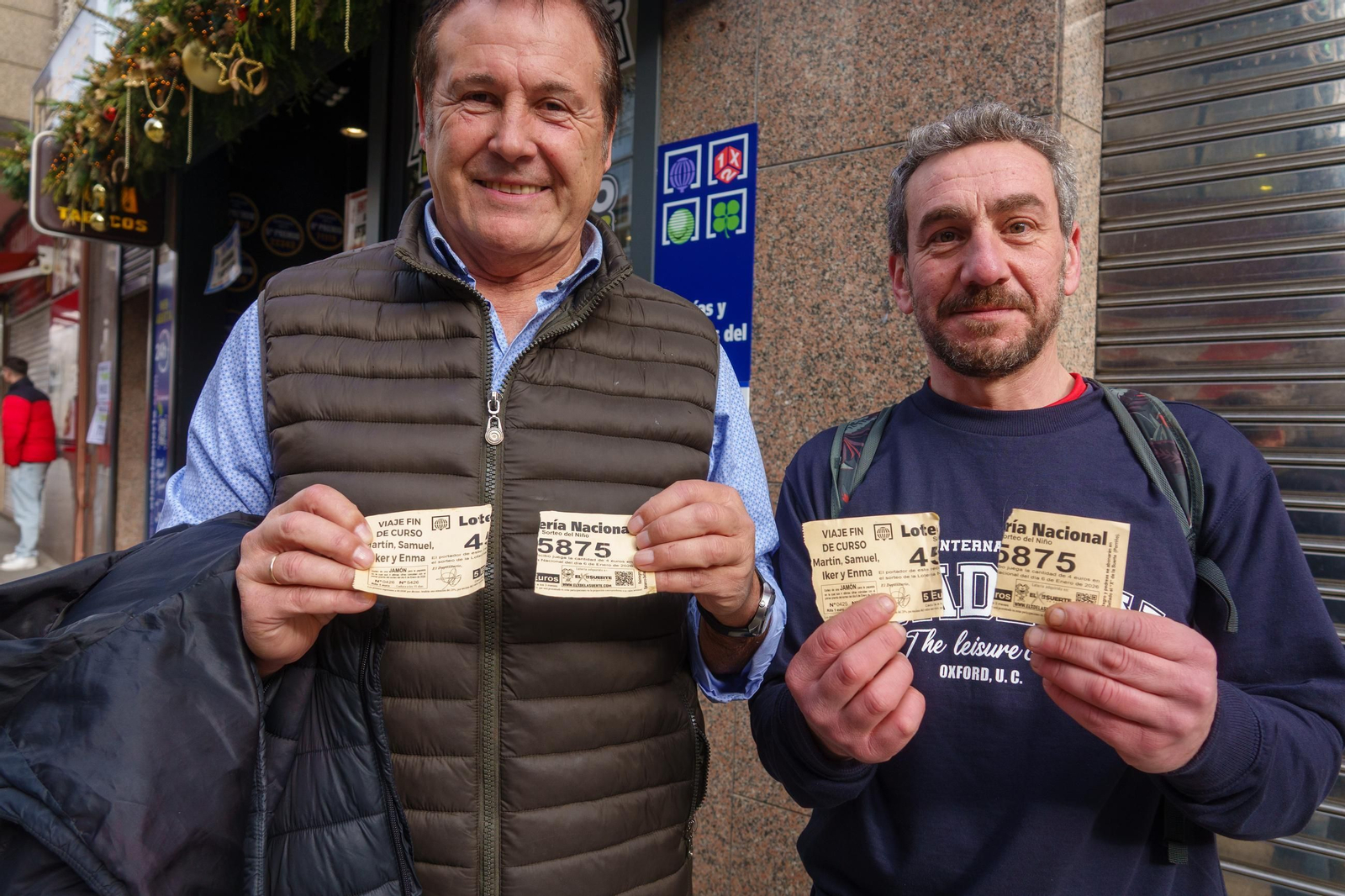 Dos de los agraciados posan con su boleto roto, que afortunadamente todavía les vale para canjear el premio.