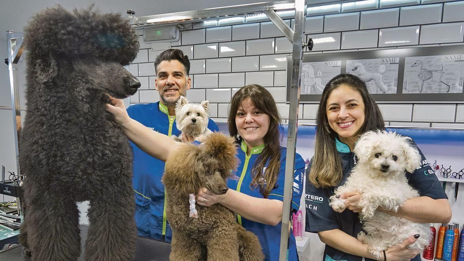 Leticia, su marido y socio en la peluquería y una de las peluqueras que trabajan en el local con tres clientes caninos.