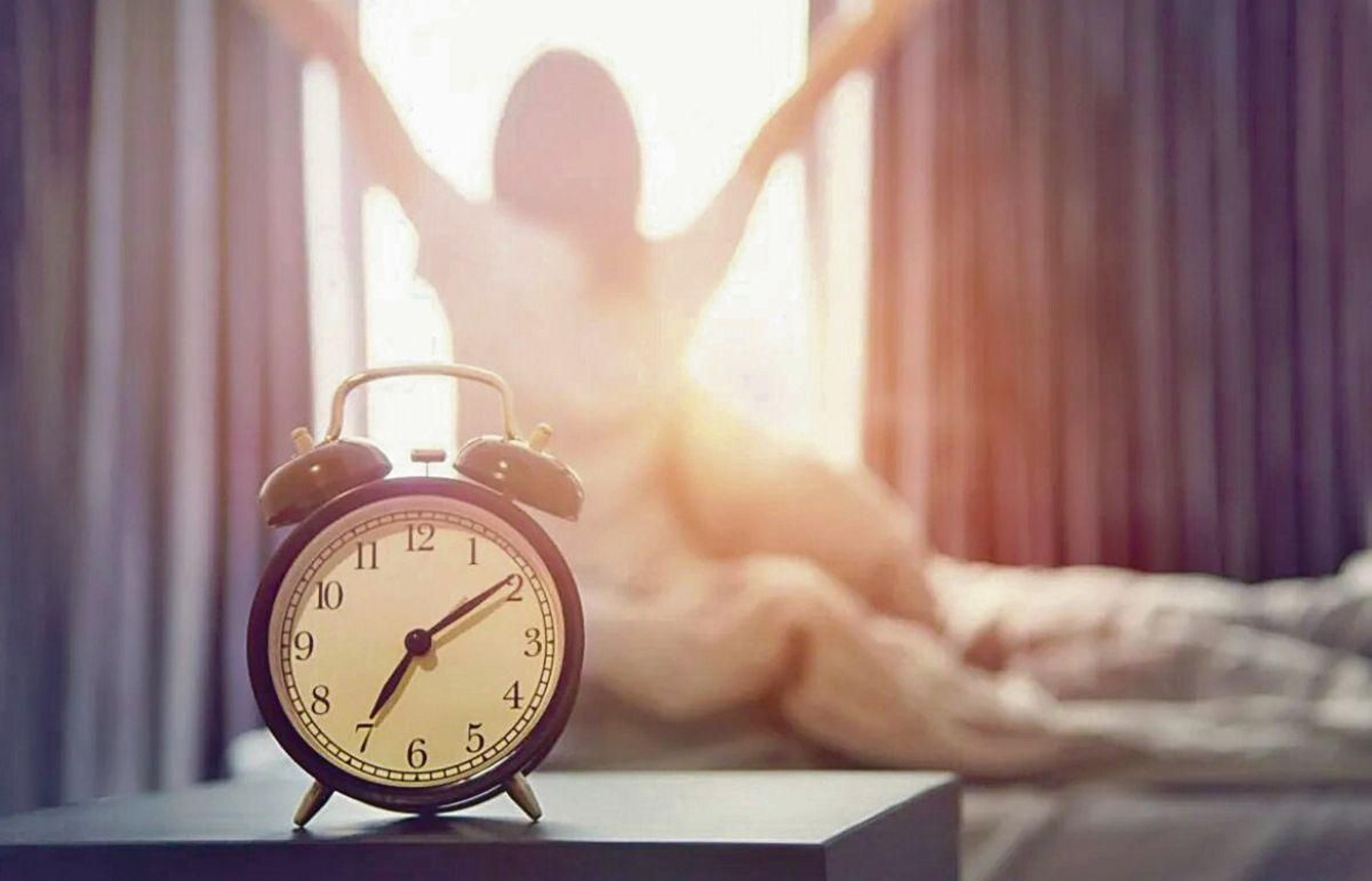 Una mujer sentada sobre una cama y recién despierta.