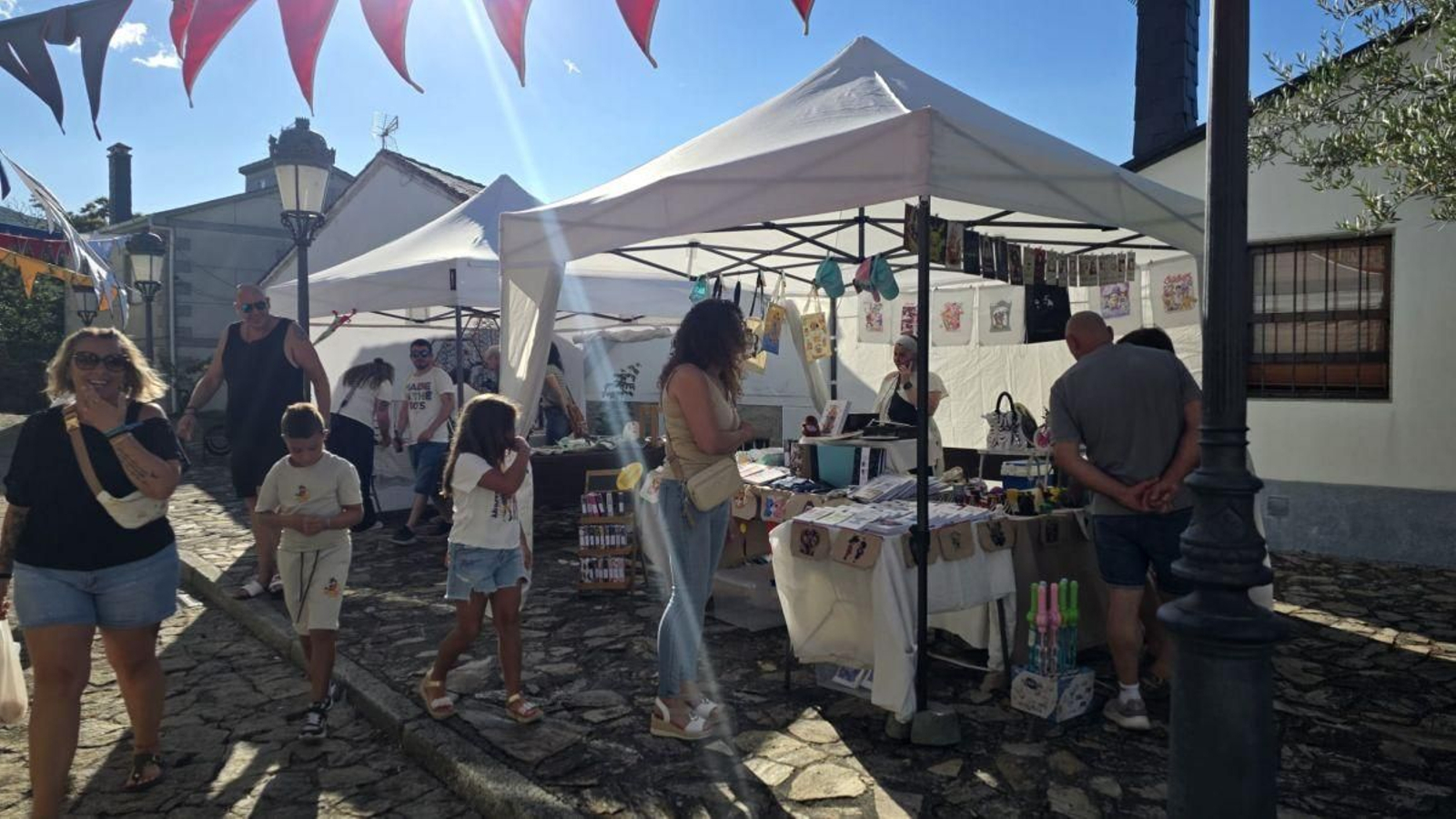 Vecinos y visitantes recorren los diferentes puestos del mercado artesanal instalado en el centro de la villa