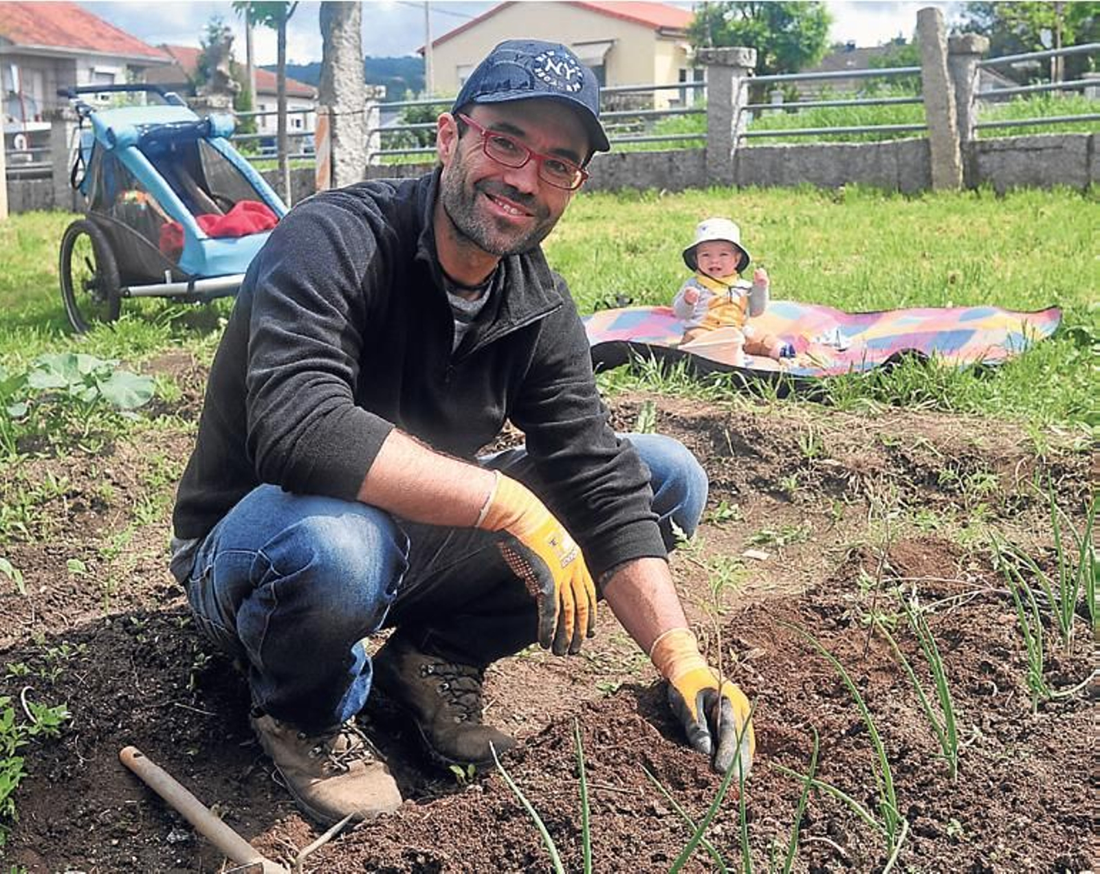 Un vecino cuida de su huerto, acompañado por su bebé