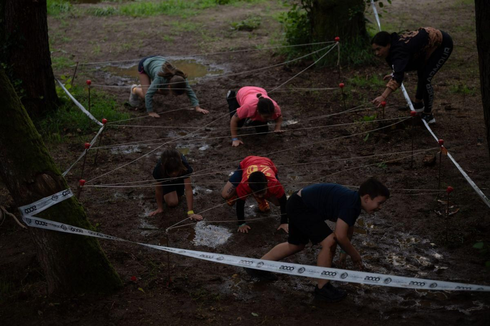 Los participantes tuvieron que agacharse para superar uno de los obstáculos marcados por la organización, con su buena dosis de barro.