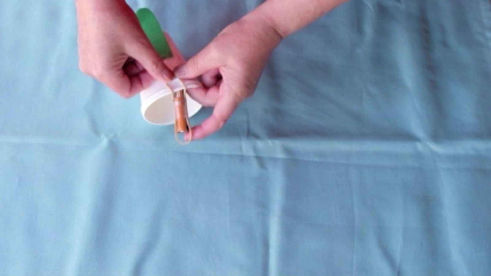 Agora que a pila e a goma están unidas, collemos os vasos e pasamos as dúas puntas que quedaron libres nas pestanas que cortamos no vaso que quedou por arriba. Engánchaa aí e pega con celo para que non escape. Xa case estamos listos para botar a andar o noso boneco.