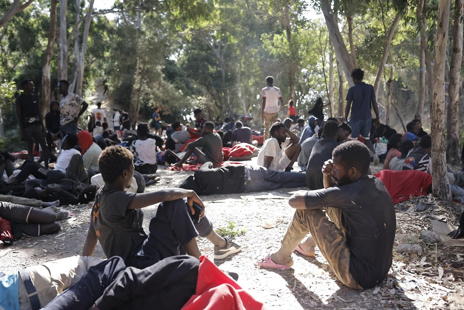 Varios migrantes descansan en una calle de Ceuta.