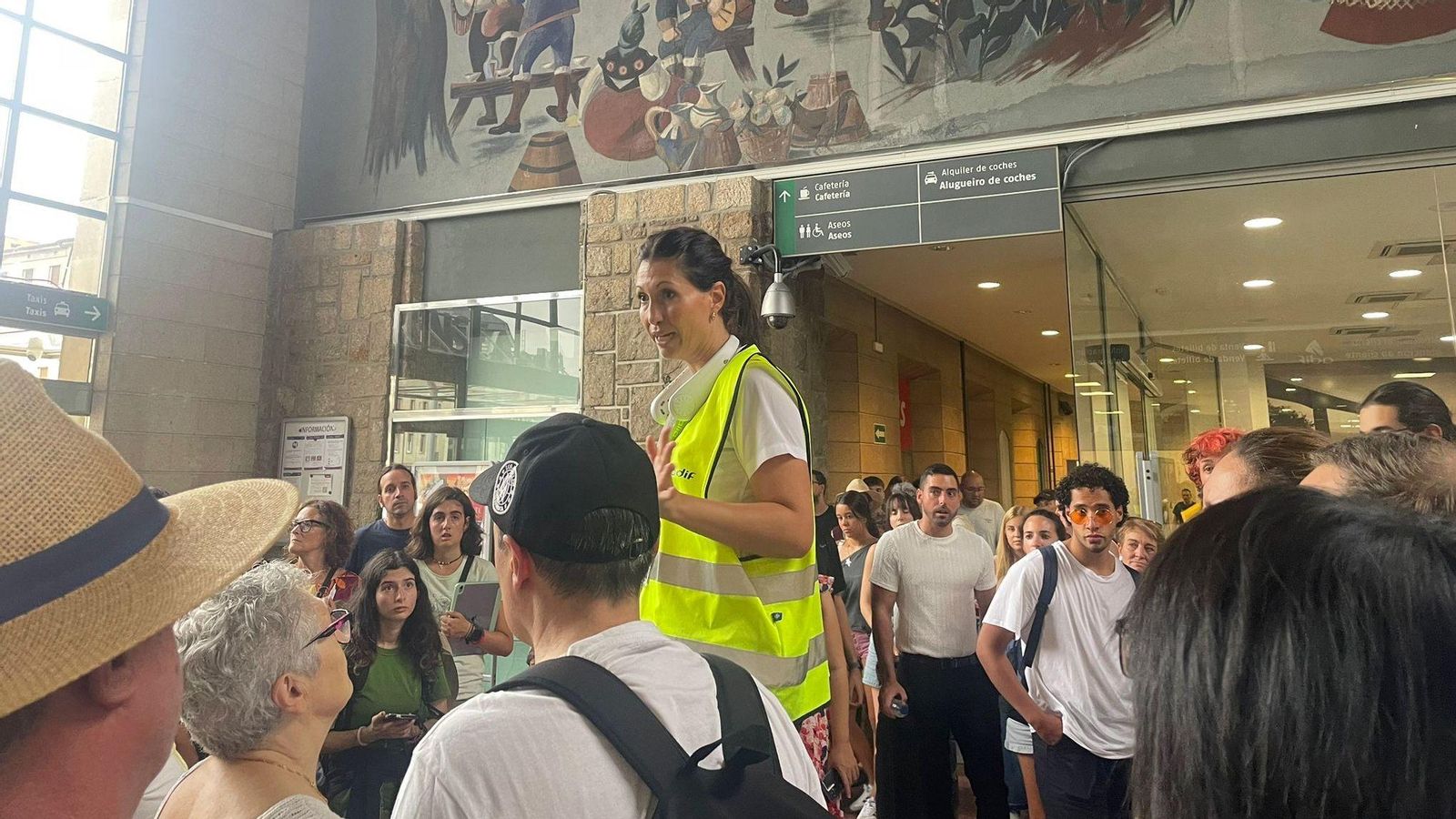 Una trabajadora de ADIF da instrucciones a los pasajeros afectados por el corte del tráfico ferroviario.