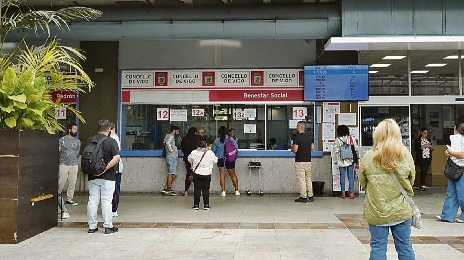 Ciudadanos haciendo cola en las ventanillas de bienestar social en la lonja del Concello.