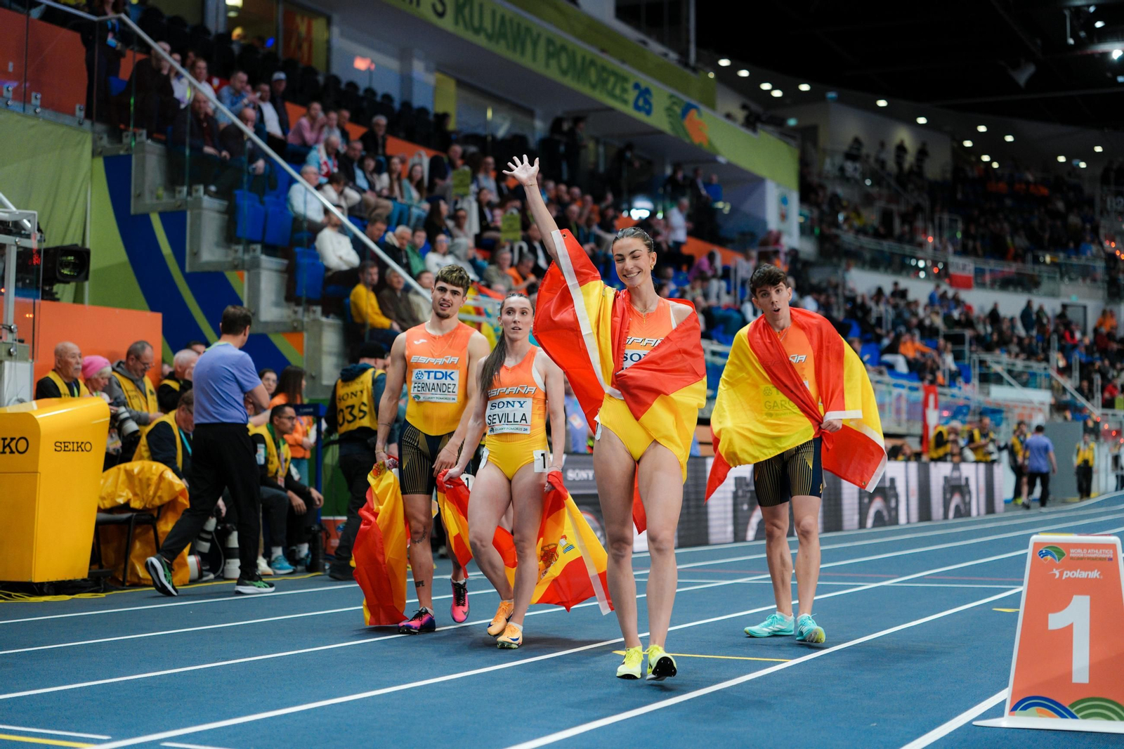 Markel Fernández, Paula Sevilla, David García Zurita y Blanca Hervás con banderas de España celebran su plata de relevos 4x400 en el Campeonato del Mundo de atletismo en pista cubierta