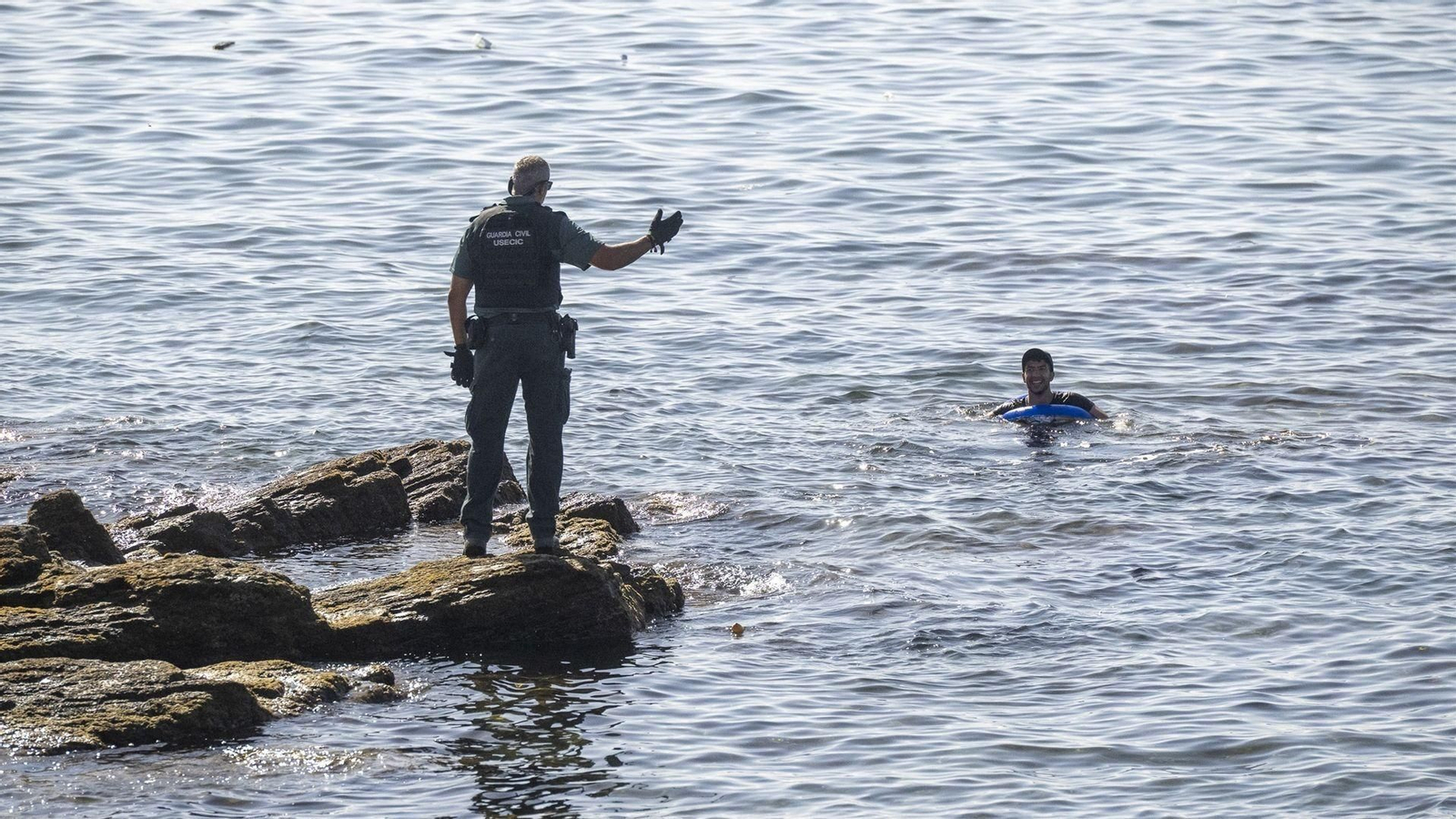 Un guardia civil avisa a una persona que nada en el mar, a 2 de agosto de 2026, en Ceuta.