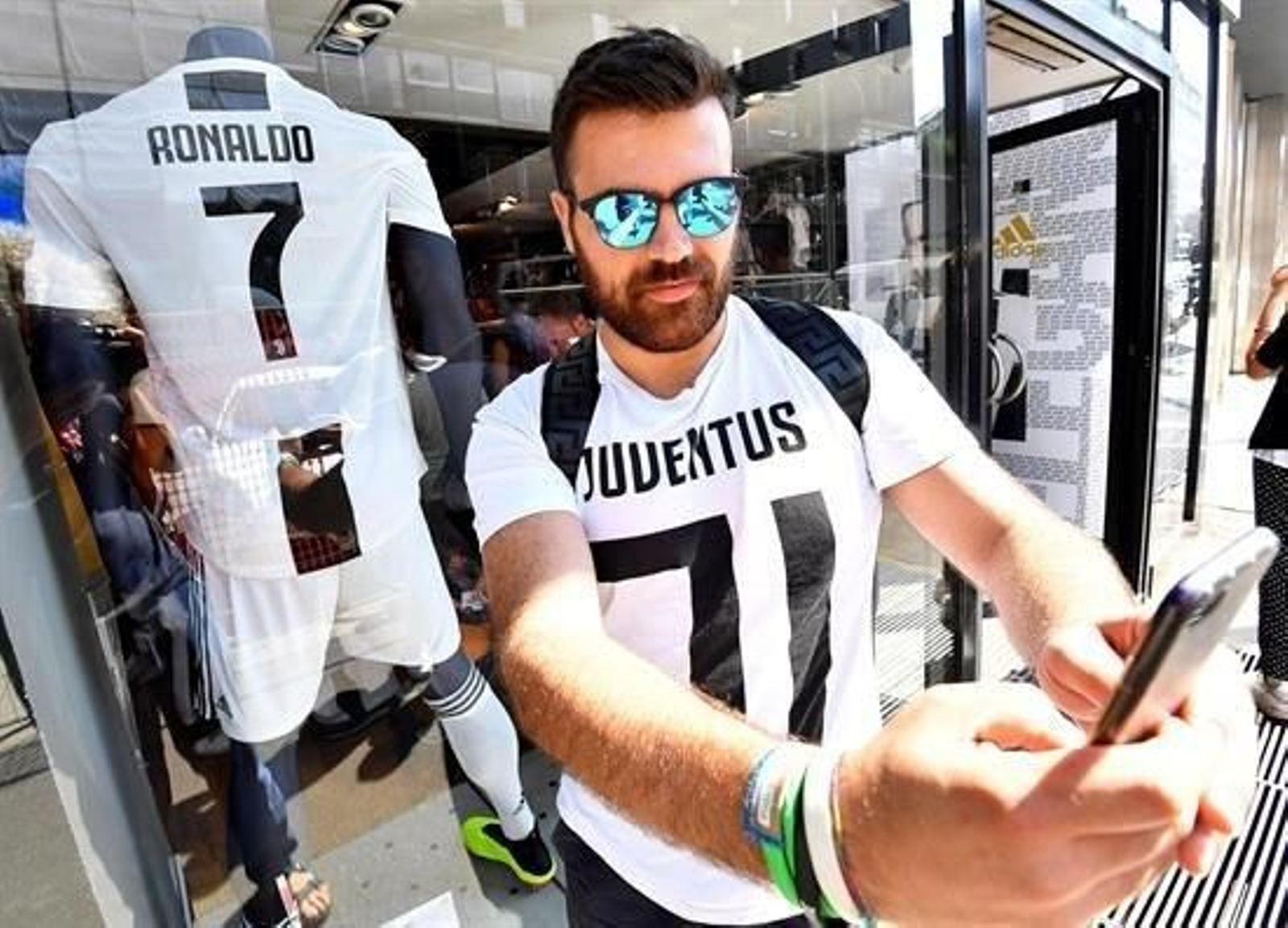 Un aficionado del Juventus posa con la nueva camiseta "bianconera" que lucirá el delantero portugués Cristiano Ronaldo frente a la tienda oficial del Juventus en Milán.