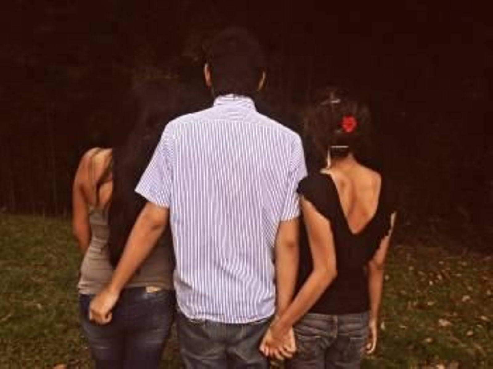 Un hombre pasea acompañado de dos mujeres por un parque.