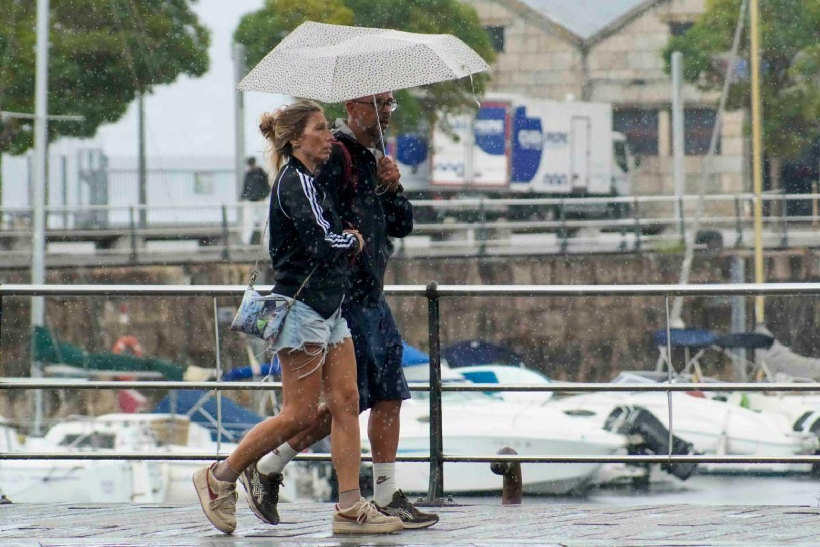 Cruceristas bajo la intensa lluvia por la mañana en Vigo.