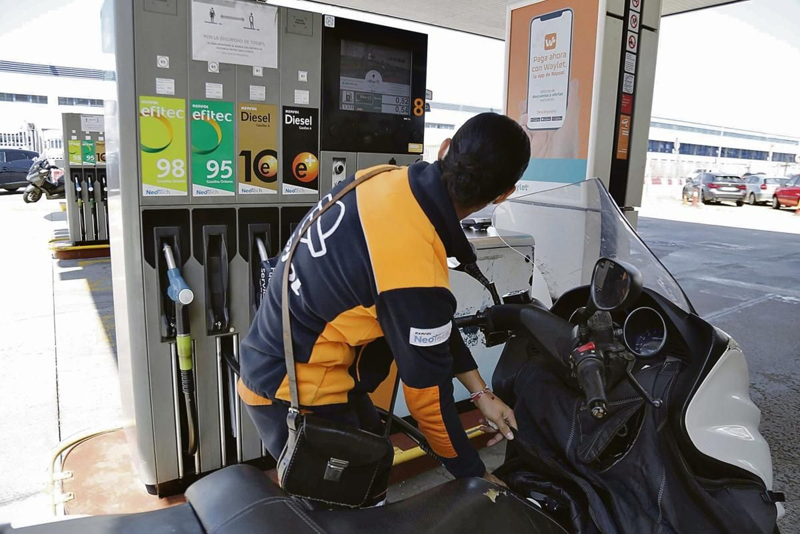 Un trabajador de una gasolinera de Vigo llena el depósitio de una moto.