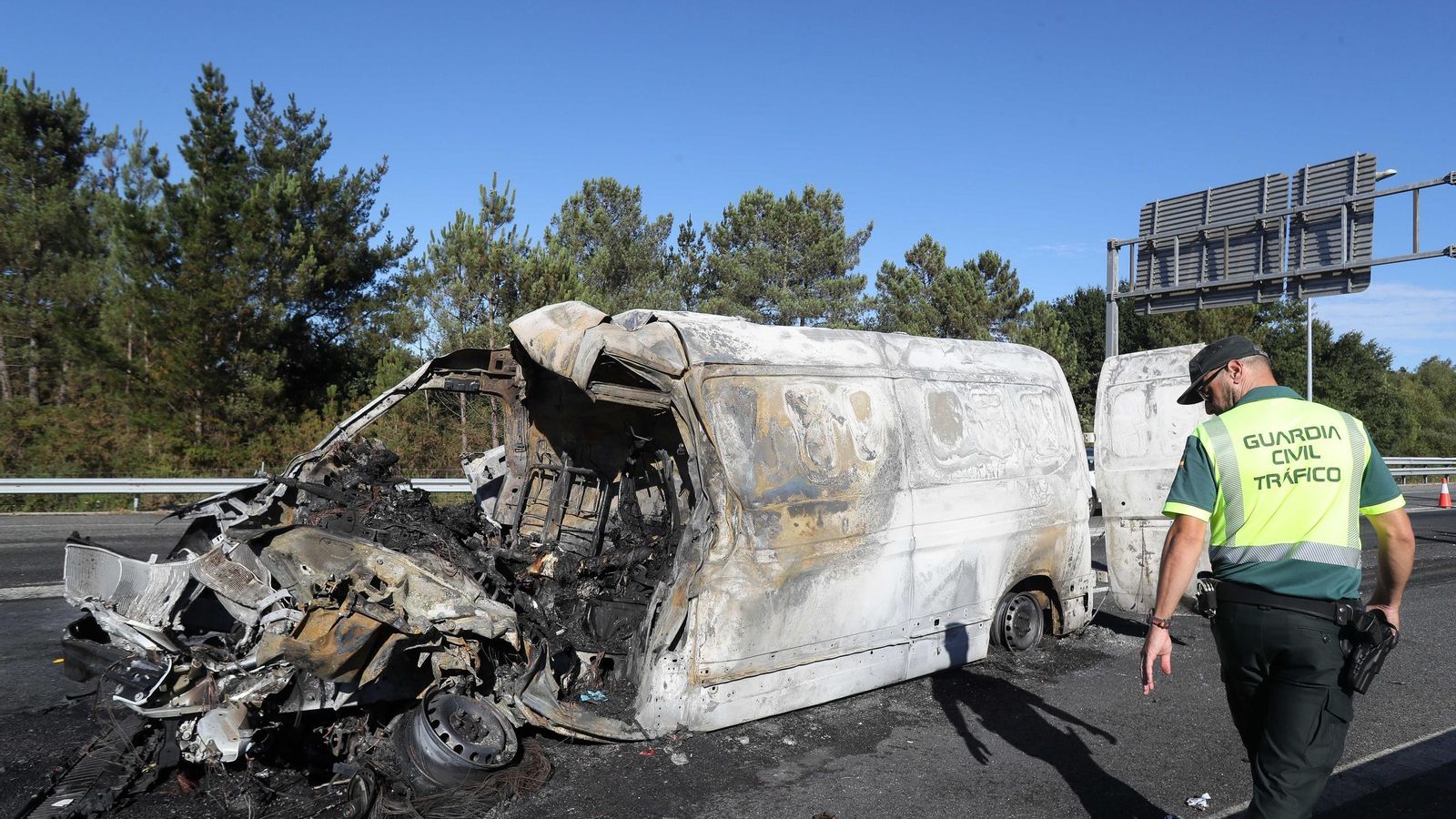 La Guardia Civil inspecciona una furgoneta calcinada.