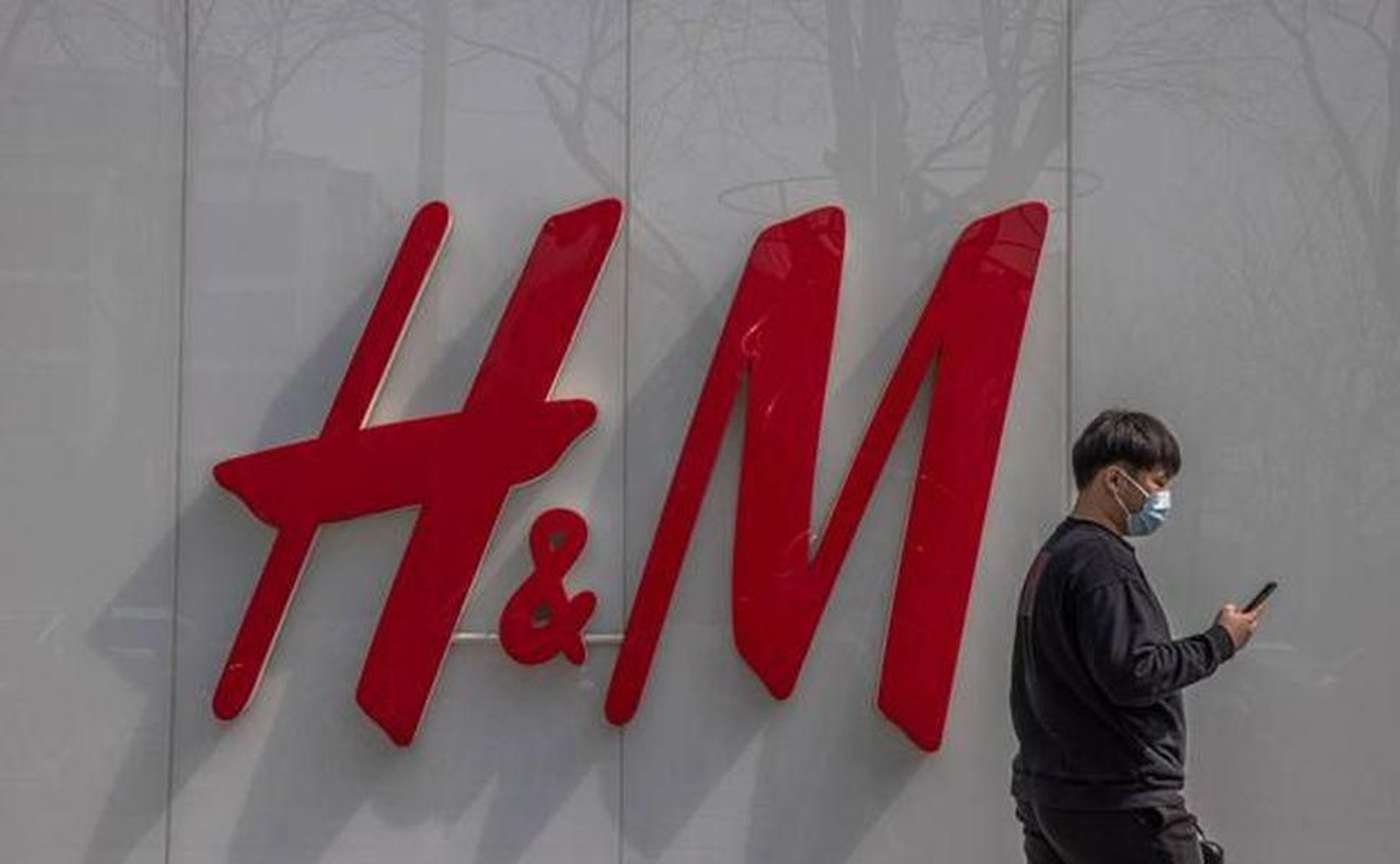 Un hombre con mascarilla pasa por delante de una tienda de H&M.