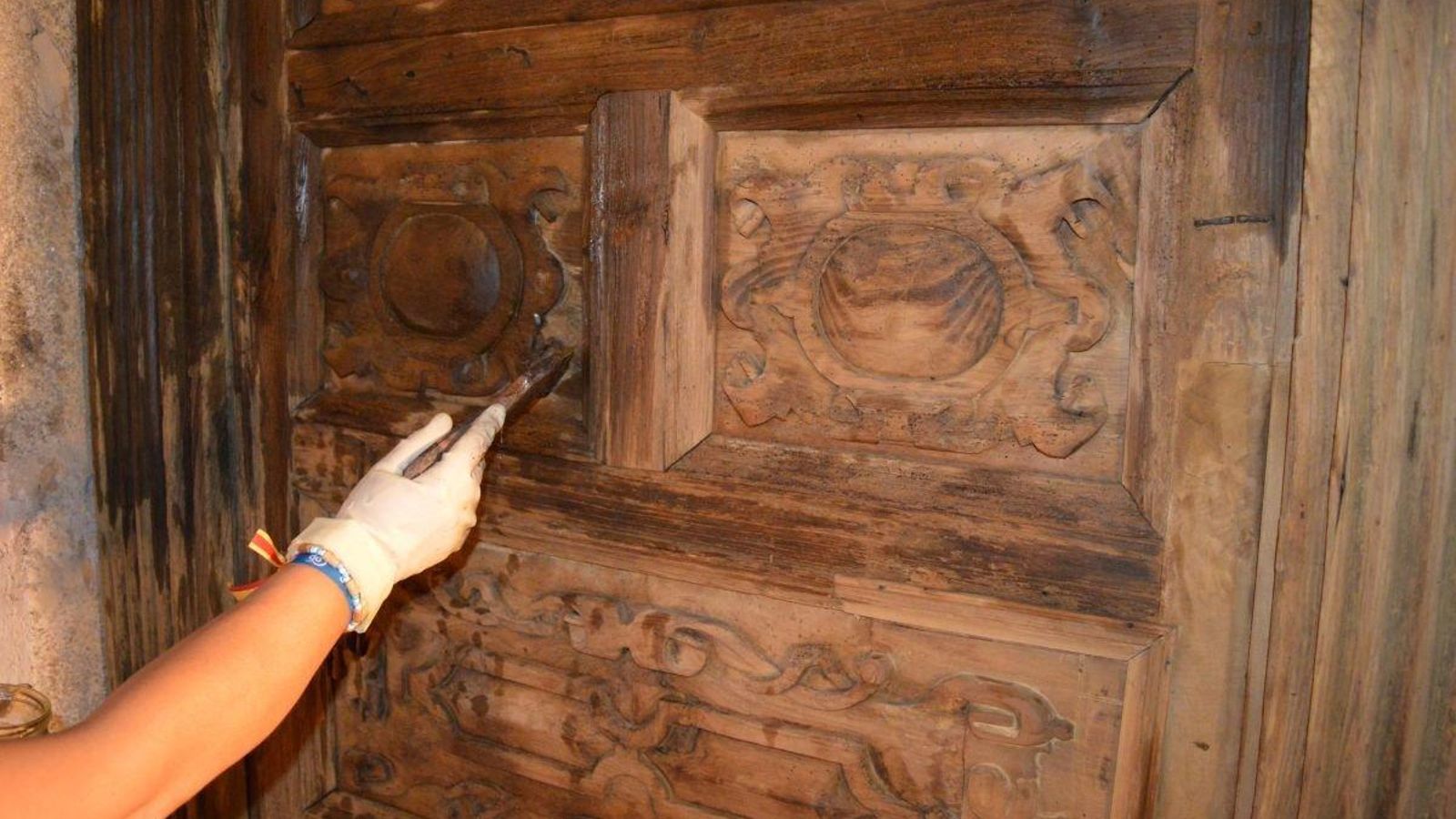 Una de las integrantes del equipo trabaja sobre las puertas del coro.