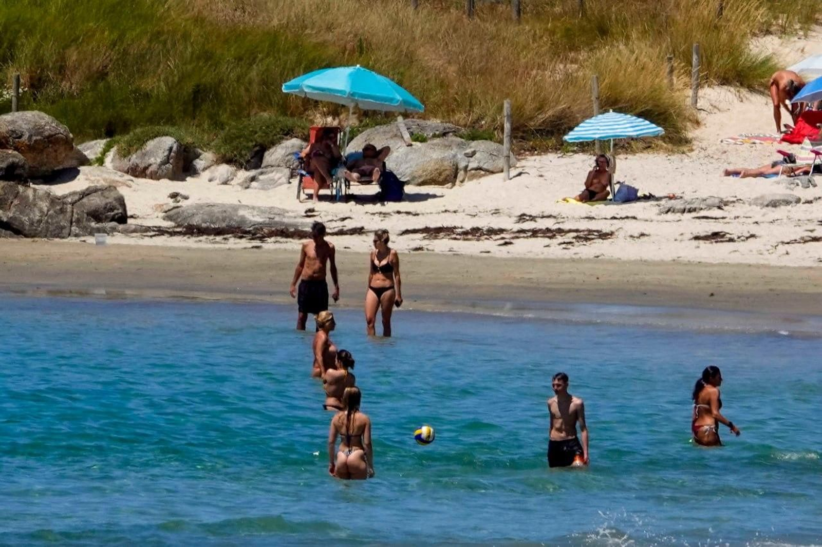Varias personas bañándose en el mar.