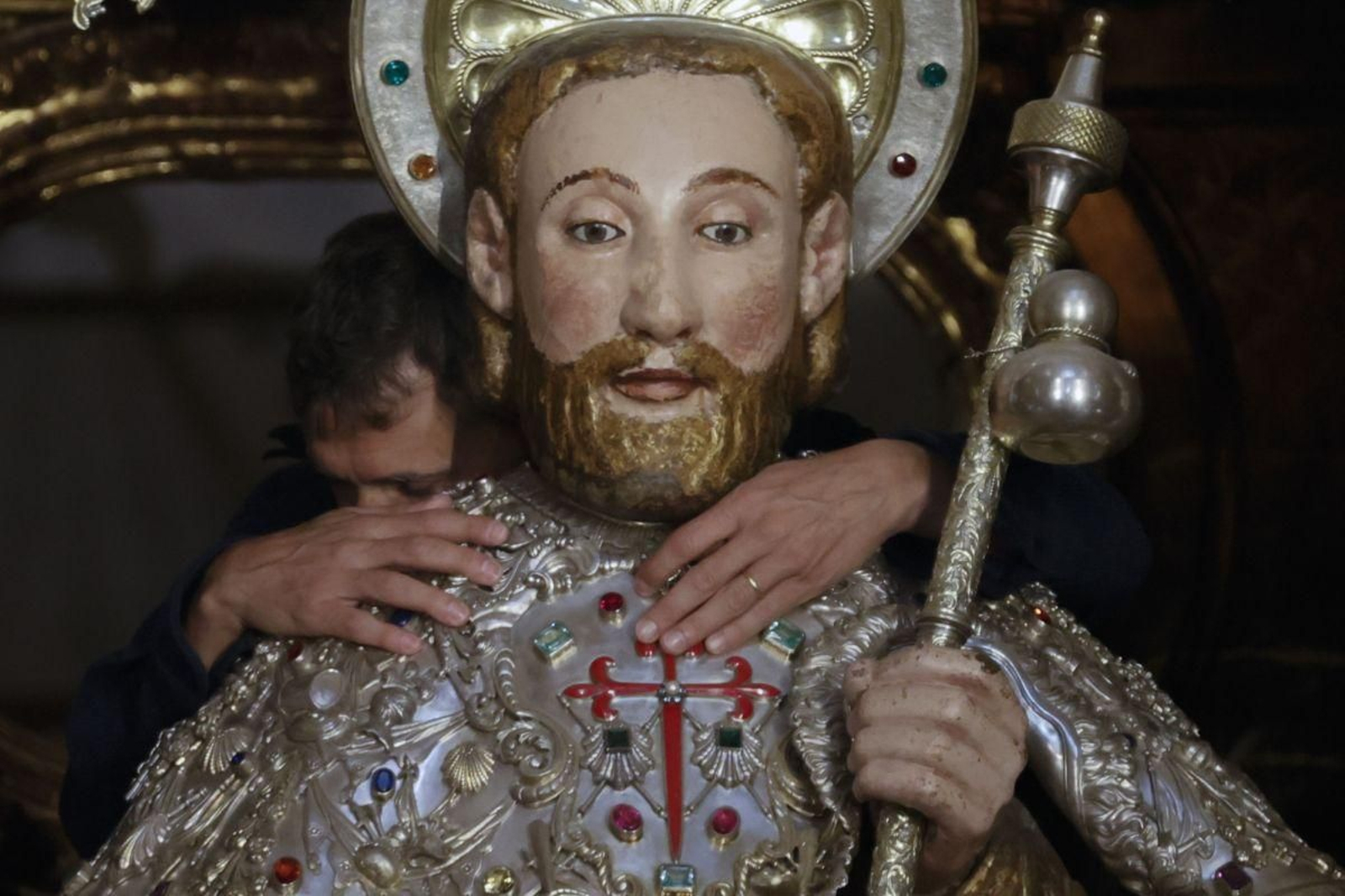 Un peregrino abraza la imagen del Apóstol Santiago.