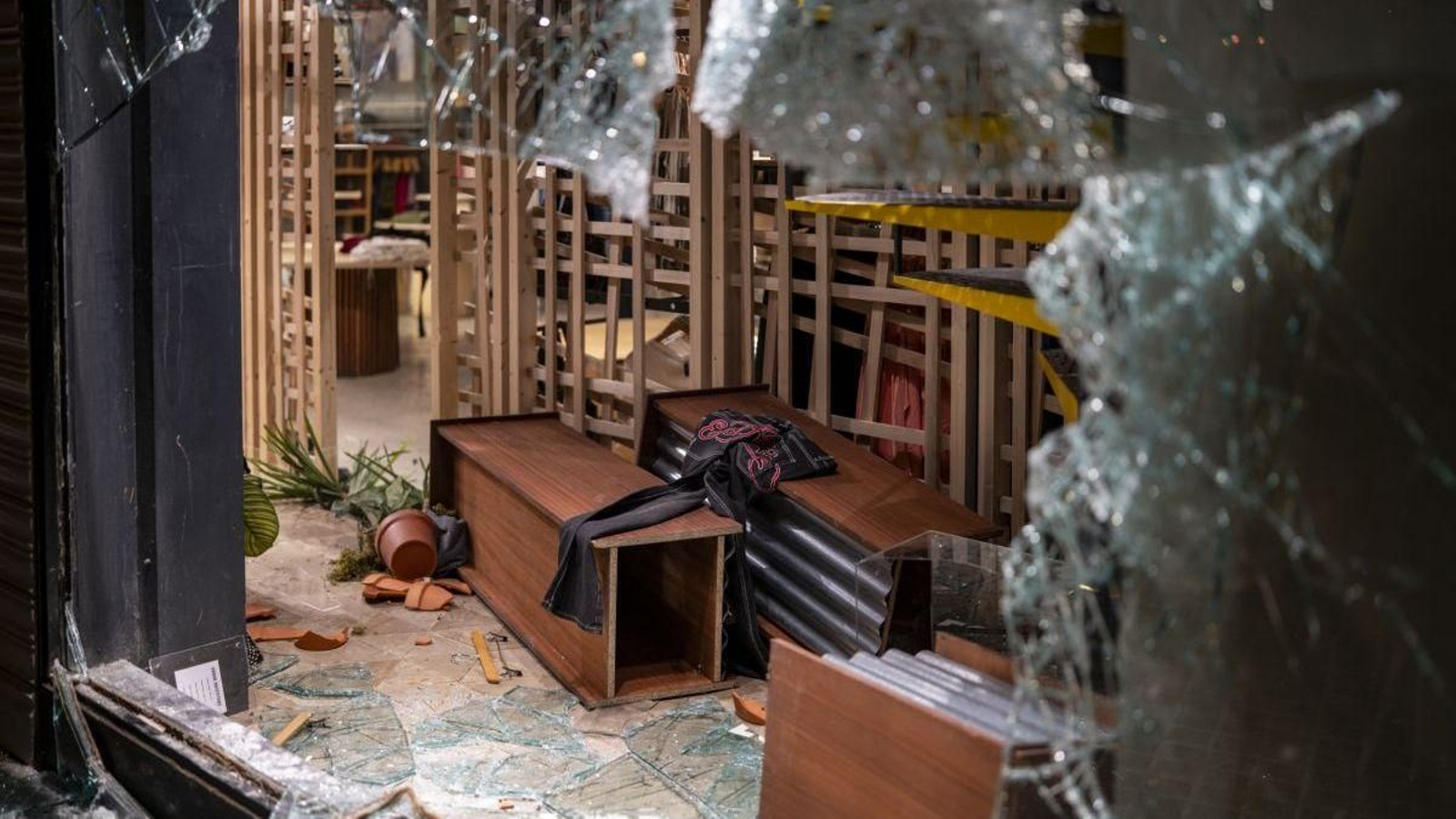 Una vidriera y estanterías rotras tras vandalizar un comercio en Barcelona.