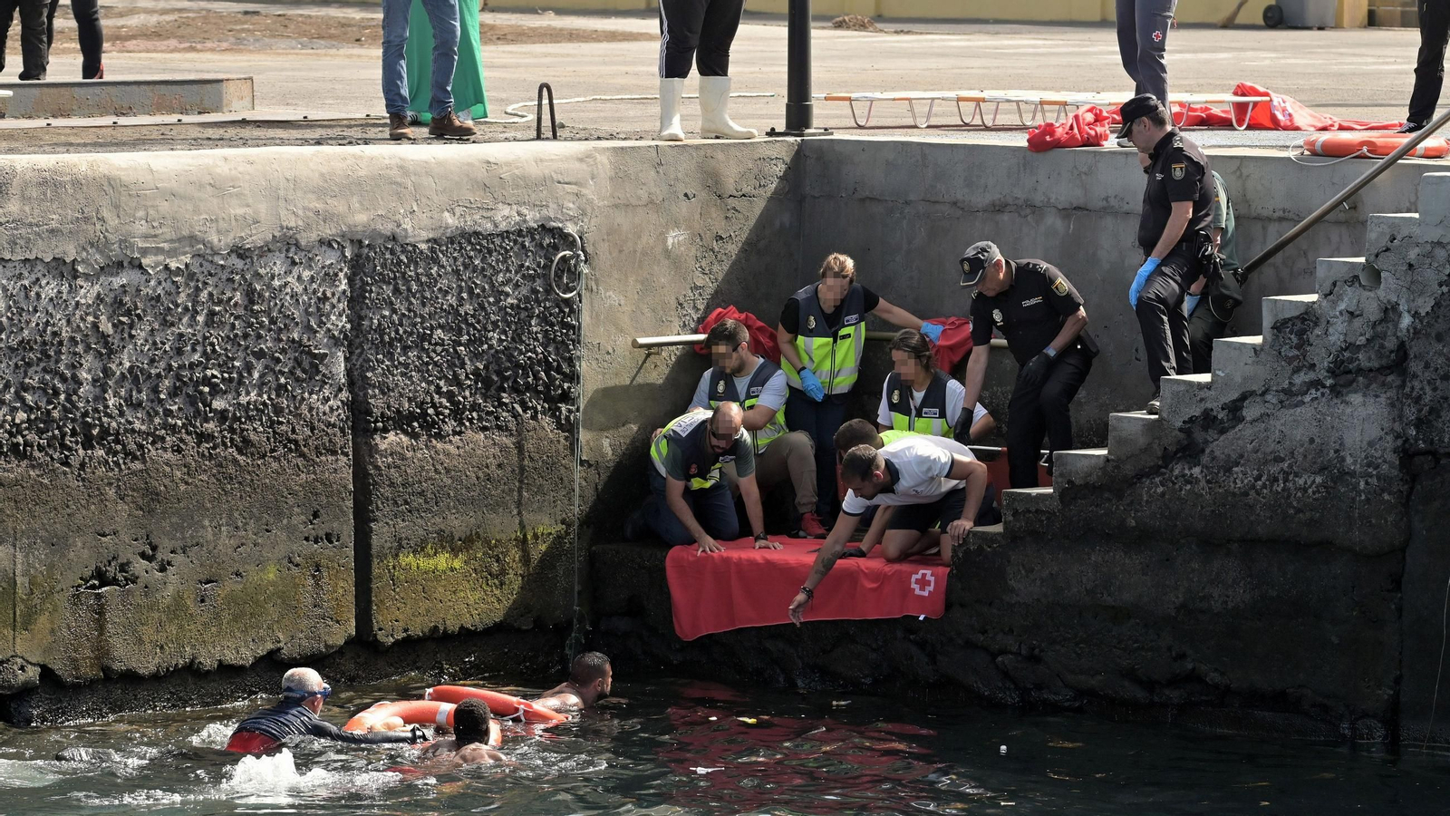 Agentes de Policía Nacional rescatan a uno de los migrantes que viajaba en el cayuco que ha volcado a su llegada al puerto de La Restinga, a 28 de mayo de 2025, en El Hierro
