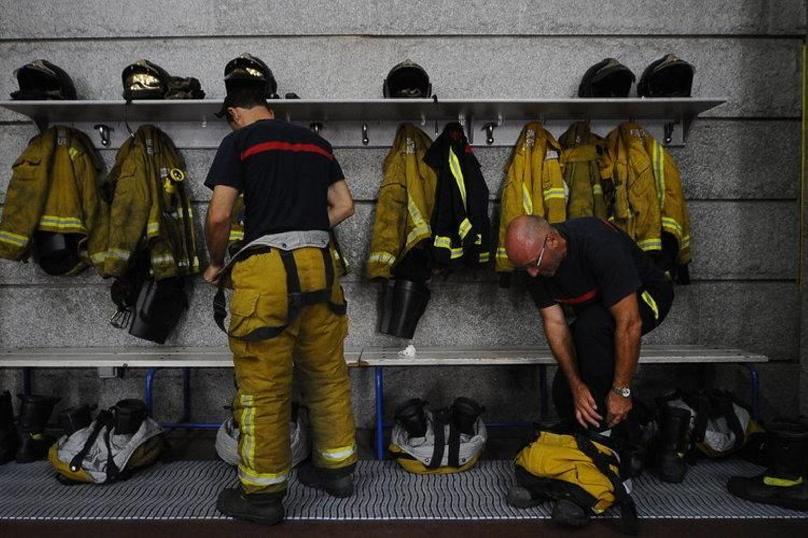 Dos bomberos del parque público de Ourense se enfundan los trajes antes de una salida.