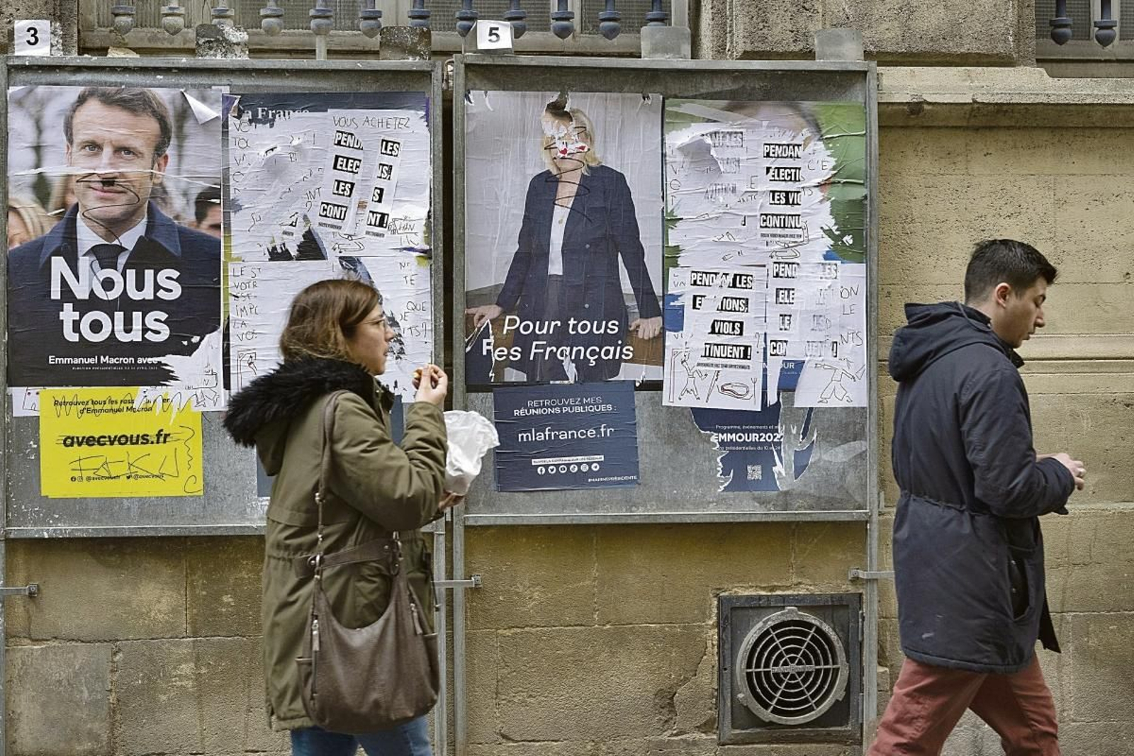 Una mujer pasa por delante de los carteles electorales de Emmanuel Macron y Marine Le Pen.