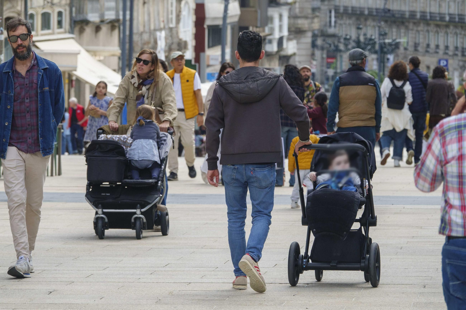 Padres y madres con sus hijos por una calle de Vigo.