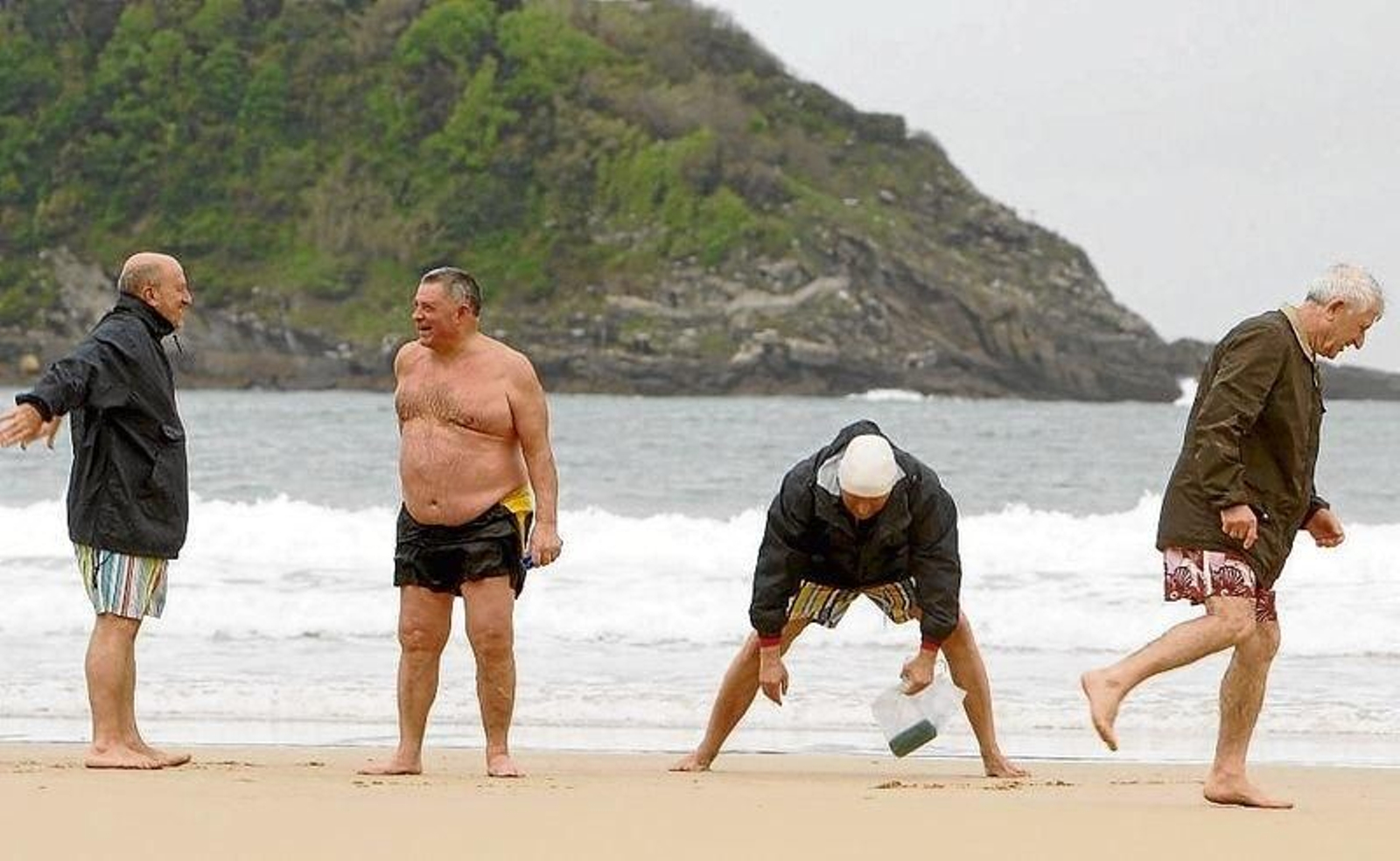Varios jubilados toman el sol y realizan ejercicios en la playa de San Sebastián.