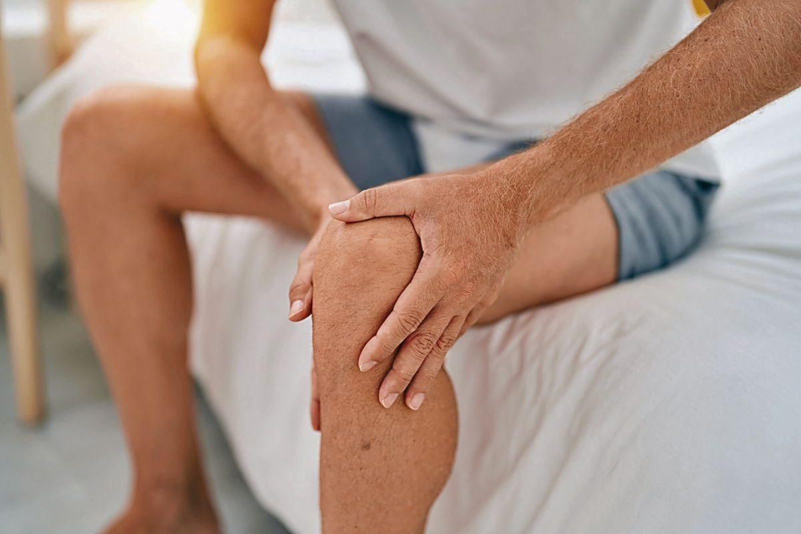 Una persona sufre dolor de rodilla al levantarse de la cama.