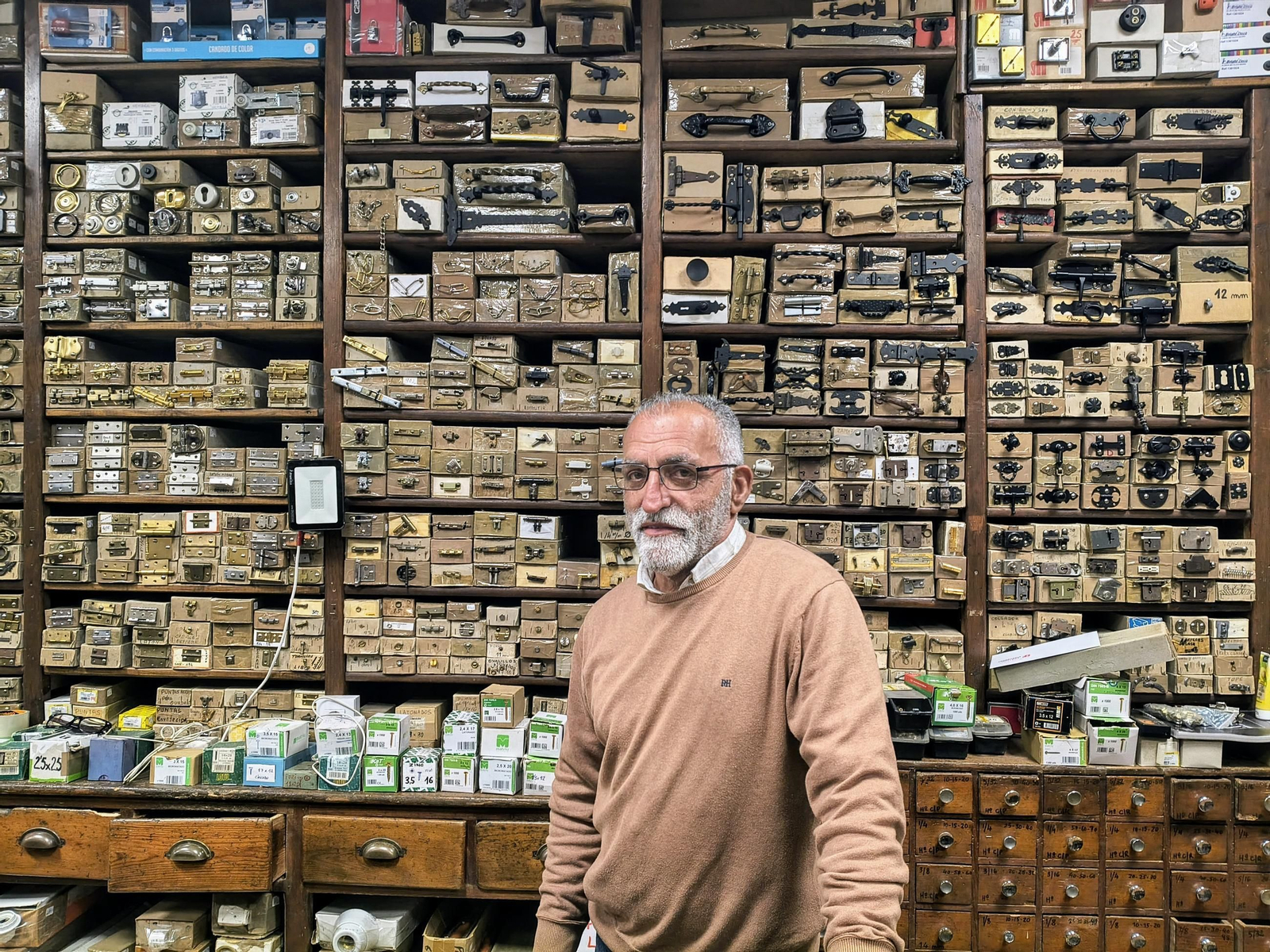 Luis Miguel Araújo en el mostrador de la Ferretería Gallega con el fondo lleno de cajas de productos.
