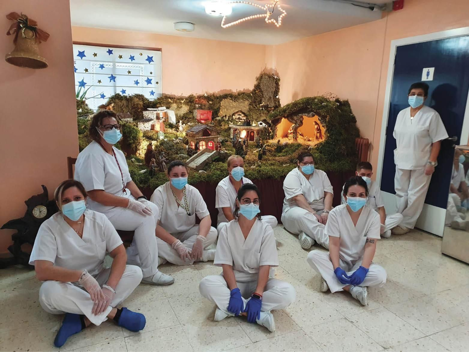 Trabajadoras de la residencia Nuestra Señora de la Esperanza posan con su belén de fondo.