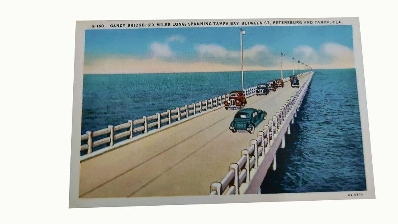 Hermosa postal de 1935 con fotografía coloreada del puente que cruza el mar entre San Petesburgo y Tampa considerado el segundo más largo del mundo, con seis millas de longitud y al que Ben-Cho-Sey considera en el texto que envía a sus hermanos una “maravilla de ingeniería”.