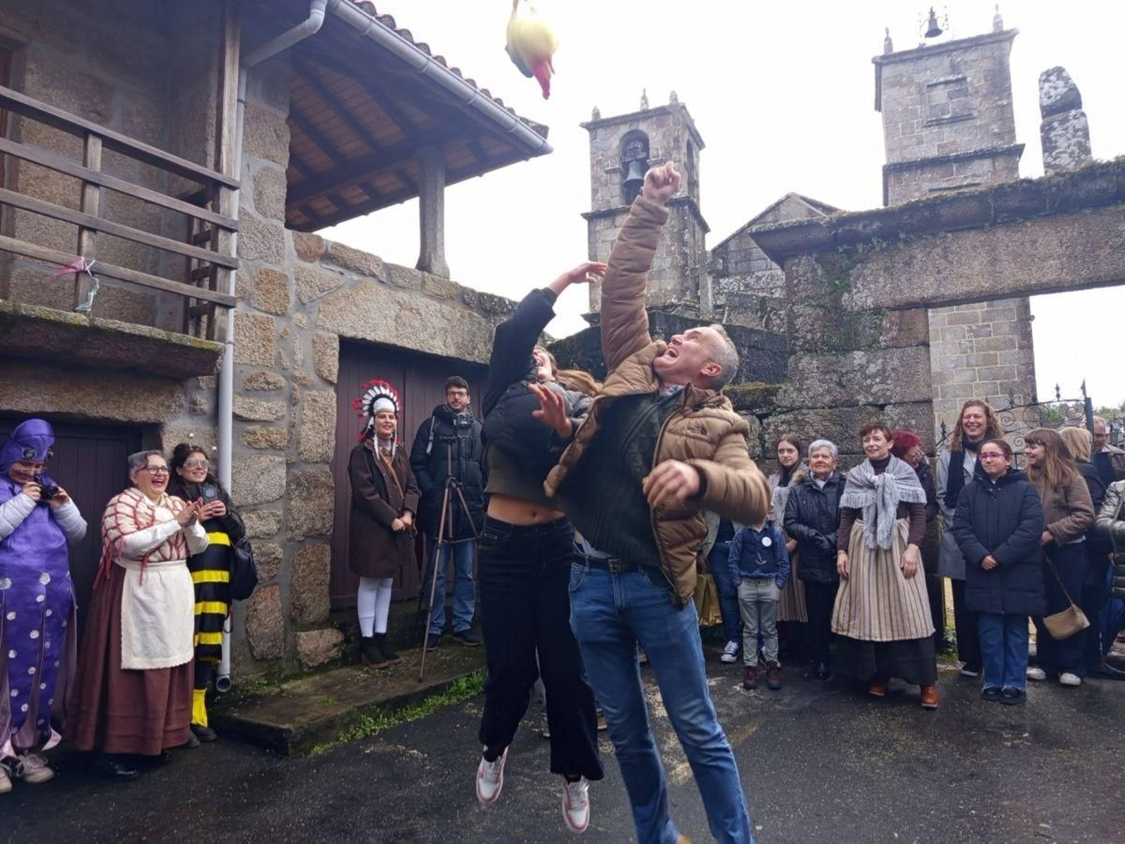 Dous dos veciños saltan para tentar coller o galo.