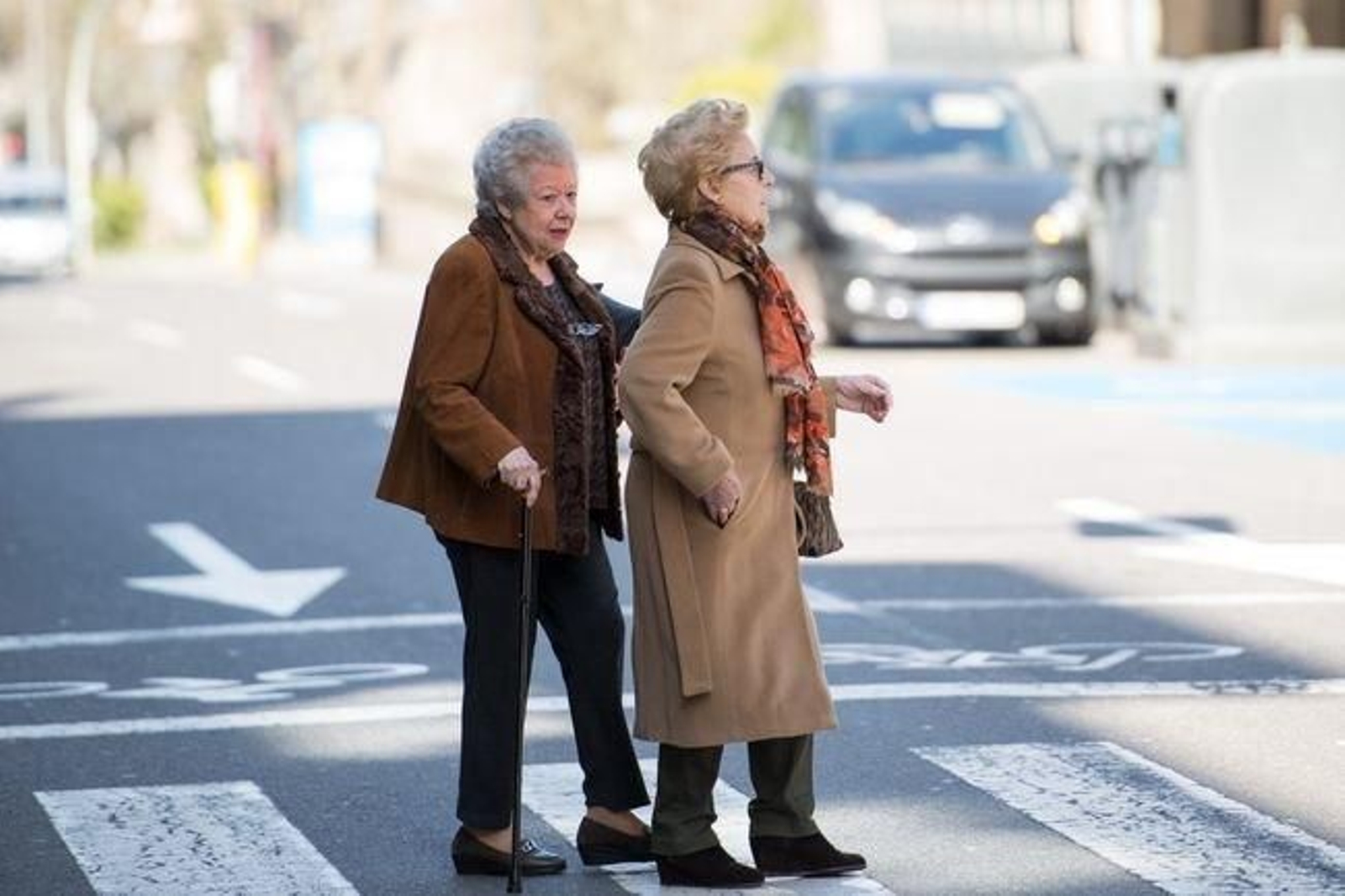 Dos mujeres mayores atraviesan un paso de peatones en la ciudad.