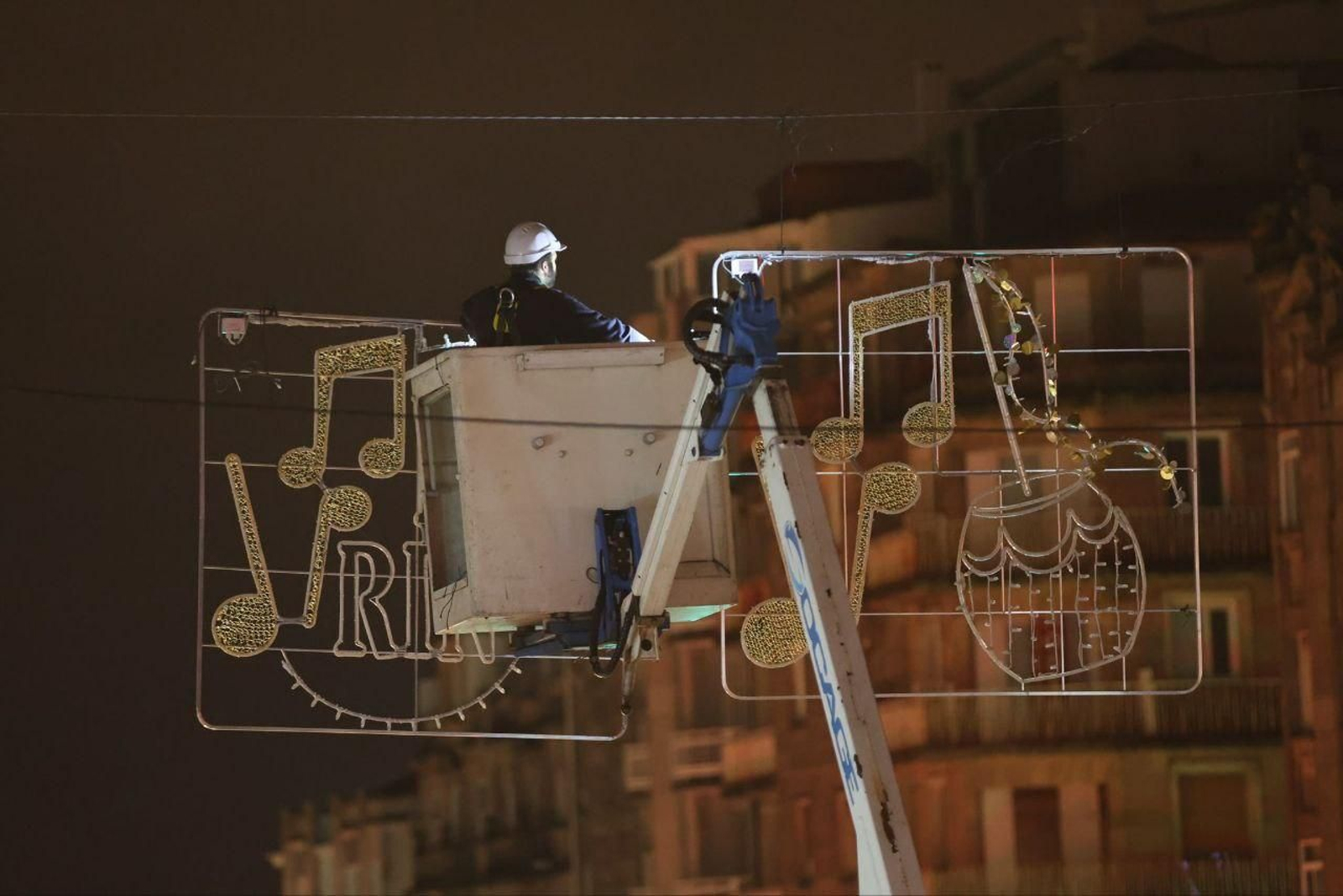 Un operario coloca las luces subido a una grúa.