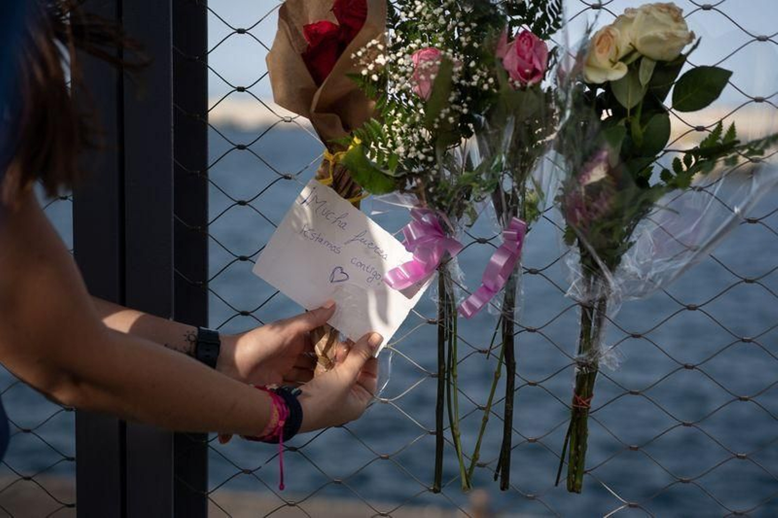 Una mujer coloca un ramo de flores en una valla del puerto de Santa Cruz de Tenerife (RAMÓN DE LA ROCHA)