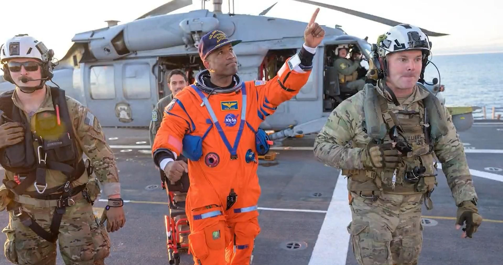 Victor Glover celebra su regreso mientras es acompañado por personal de la Marina en la cubierta del buque de recuperación.