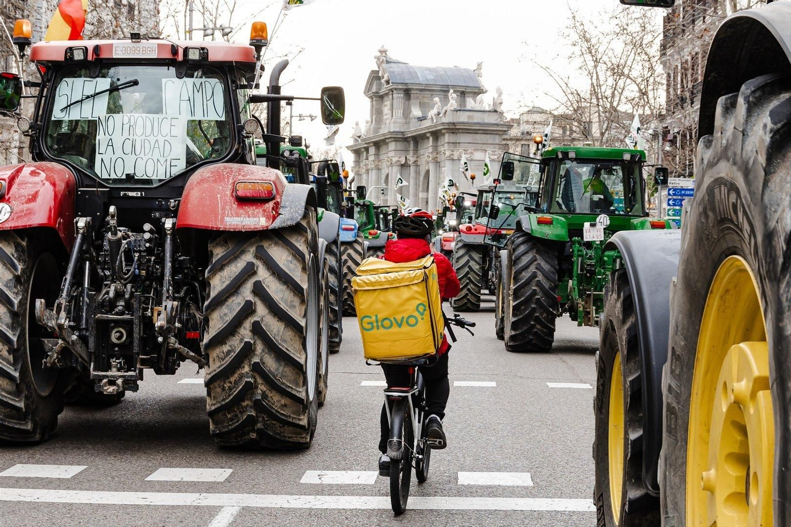 Decenas de tractores llegan a la capital en protesta por las condiciones del agro. En la imagen, un repartidor de Glovo se hace hueco entre ellos (EP)
