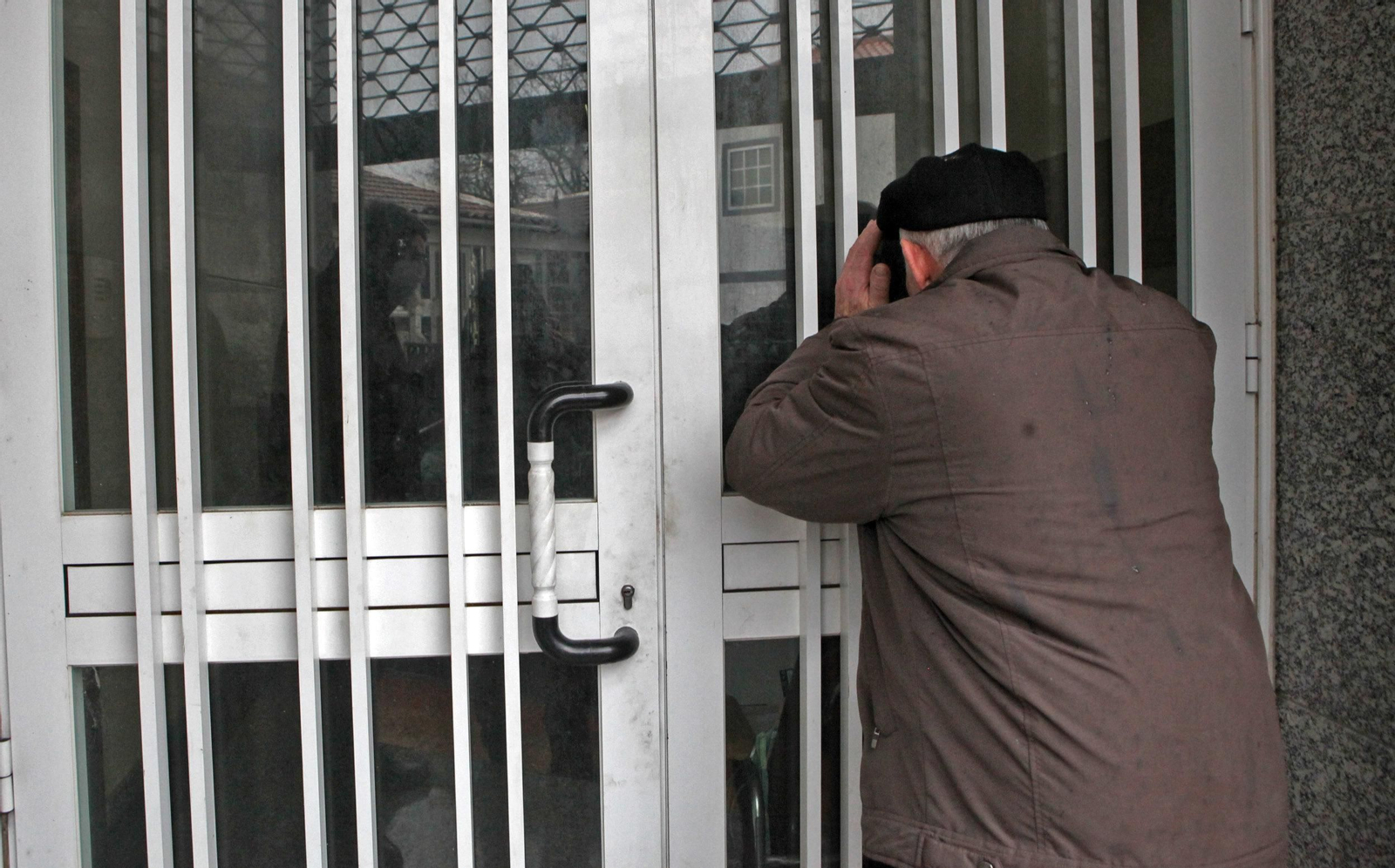 Un vecino mira por la puerta que forzaron los asaltantes para acceder al edificio.