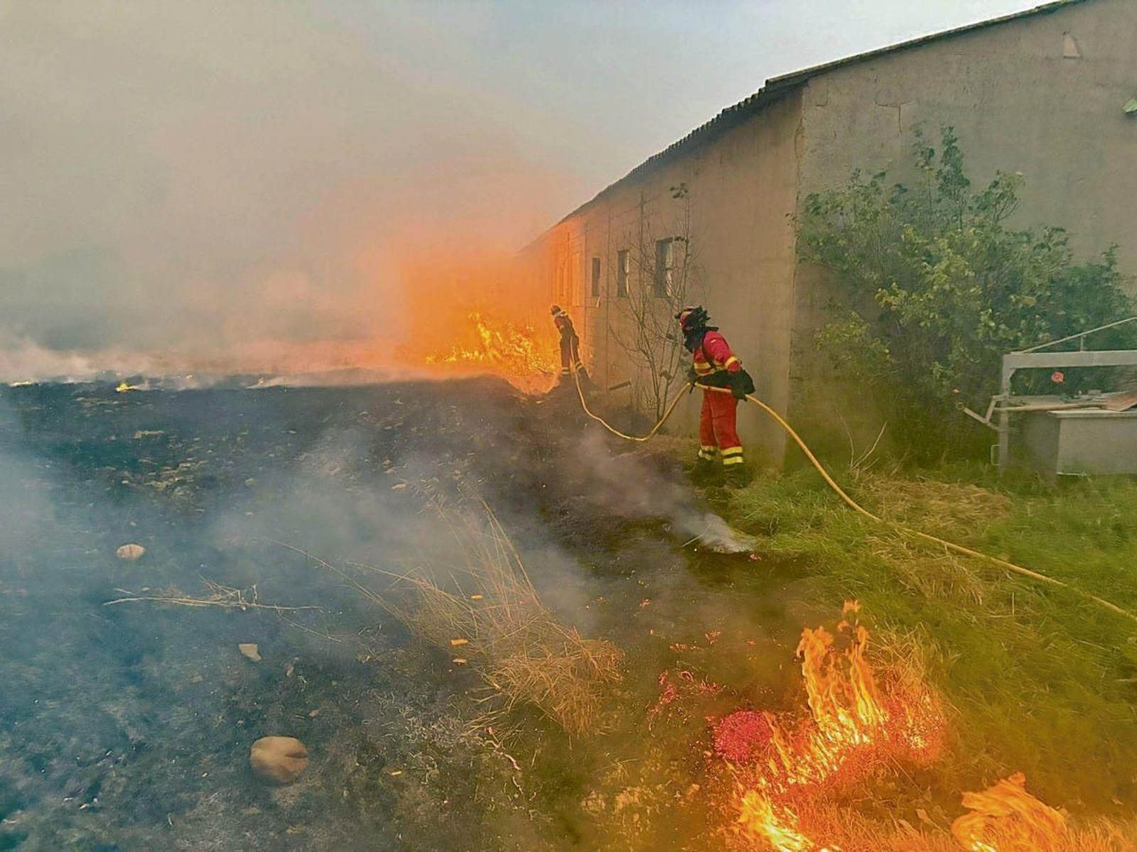Los servicios de extinción tratan de proteger una construcción en el incendio de Molezuelas-Castrocalbón, en León.