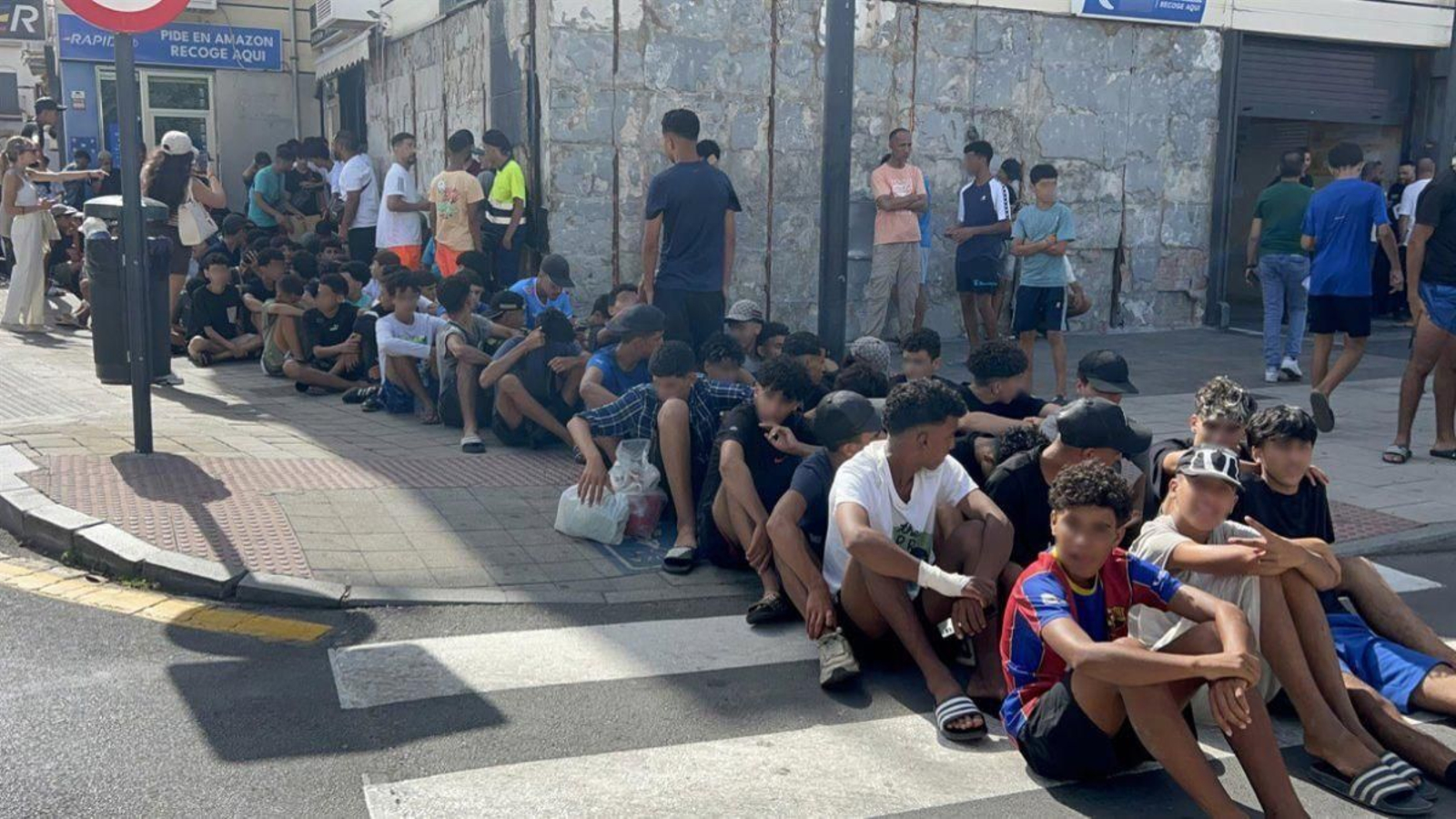 Un grupo de menores espera para ser filiado en una comisaría de la Policía Nacional en Ceuta.