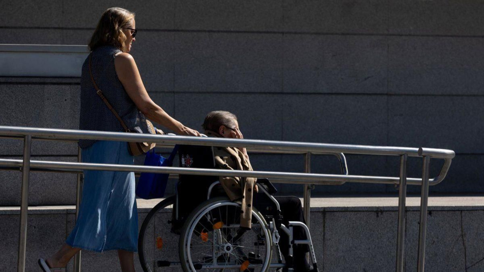 Una cuidadora da un paseo con una mujer en silla de ruedas.