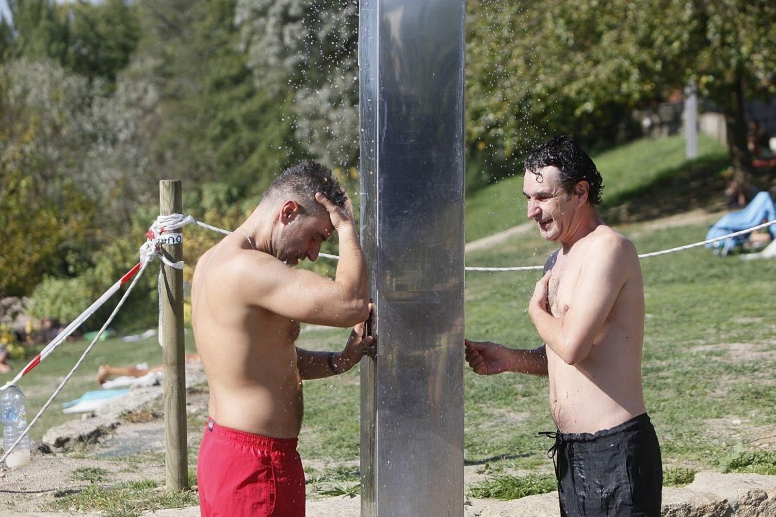 Dos hombres alivian el calor con un ducha en A Chavasqueira.